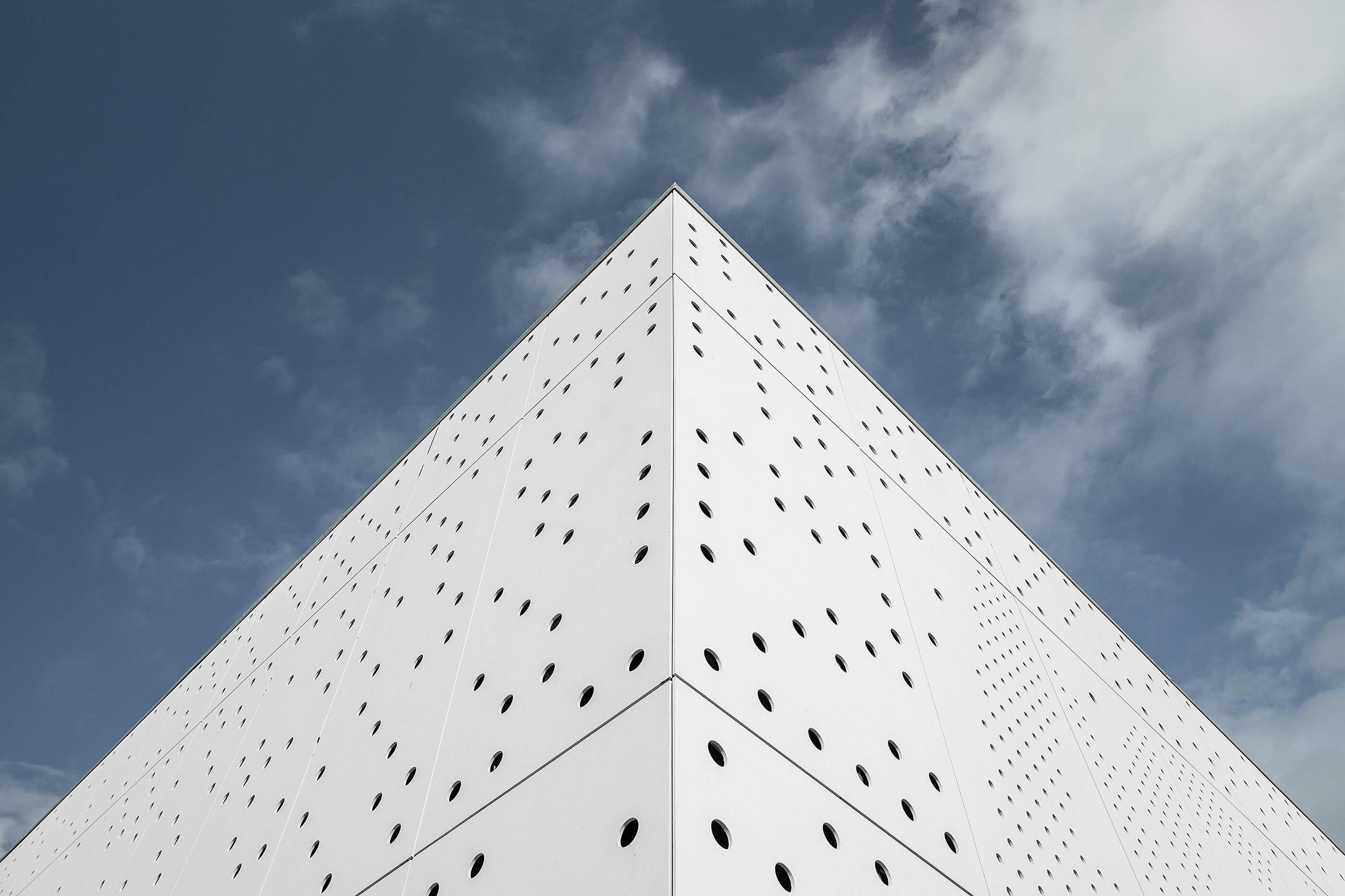 Canto do edifício com fachada branca perfurada e céu azul. Design minimalista e moderno. — Academia20 arquitetura StudioWorkers em Espinho