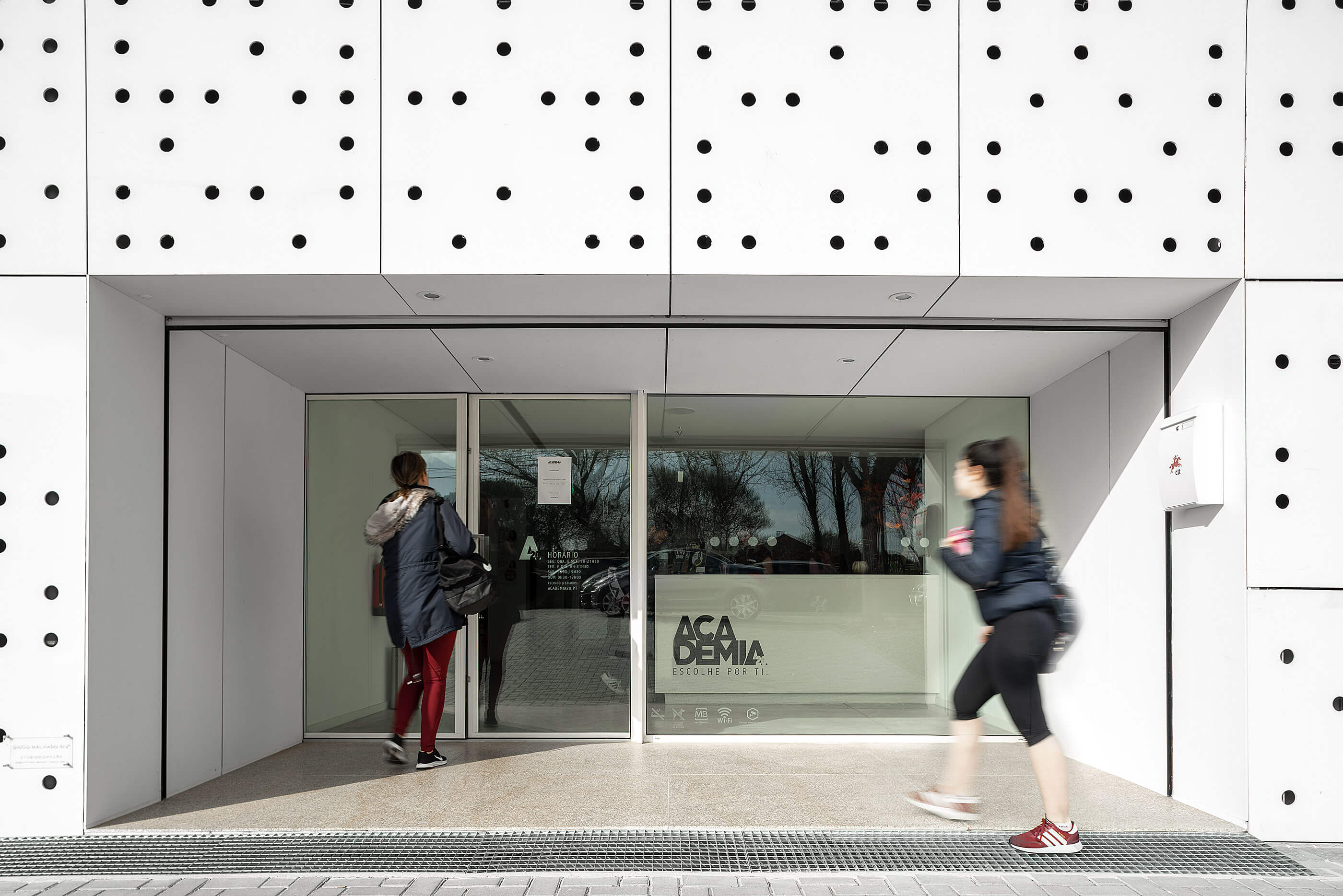 Entrada do edifício com fachada perfurada e porta de vidro. Logótipo da academia. — Academia20 arquitetura StudioWorkers em Espinho