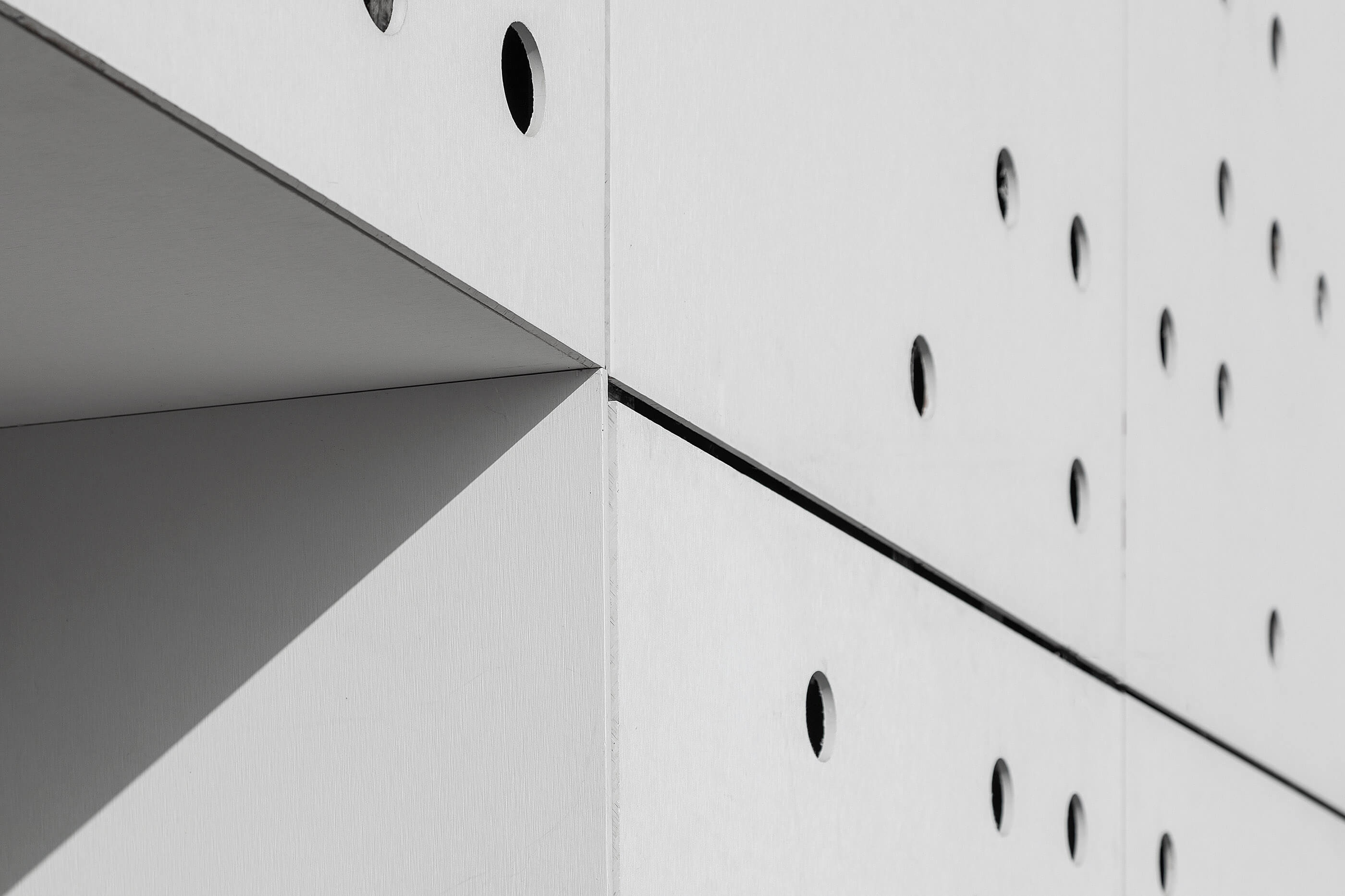 Detalhe da fachada branca com painéis perfurados. Design geométrico e minimalista. — Academia20 arquitetura StudioWorkers em Espinho