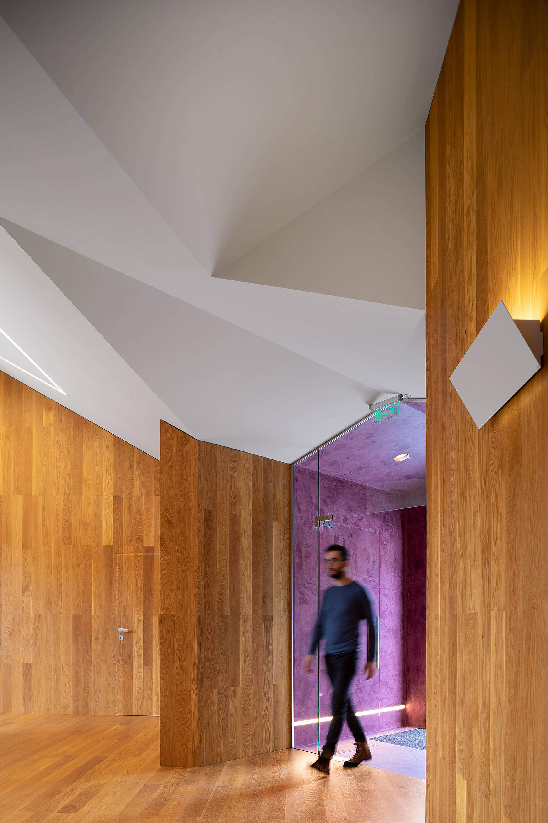 Hall de entrada com paredes de madeira clara, teto geométrico branco e porta roxa. — Adega do Castanheirinho arquitetura João Albano Arquitecto em Águeda