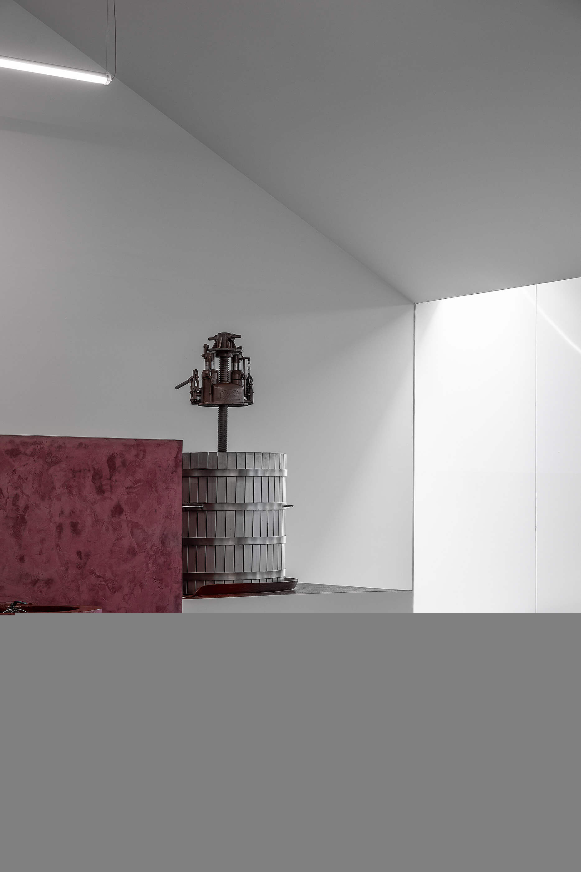 Interior da adega com prensa de vinho antiga e paredes brancas minimalistas. — Adega do Castanheirinho arquitetura João Albano Arquitecto em Águeda