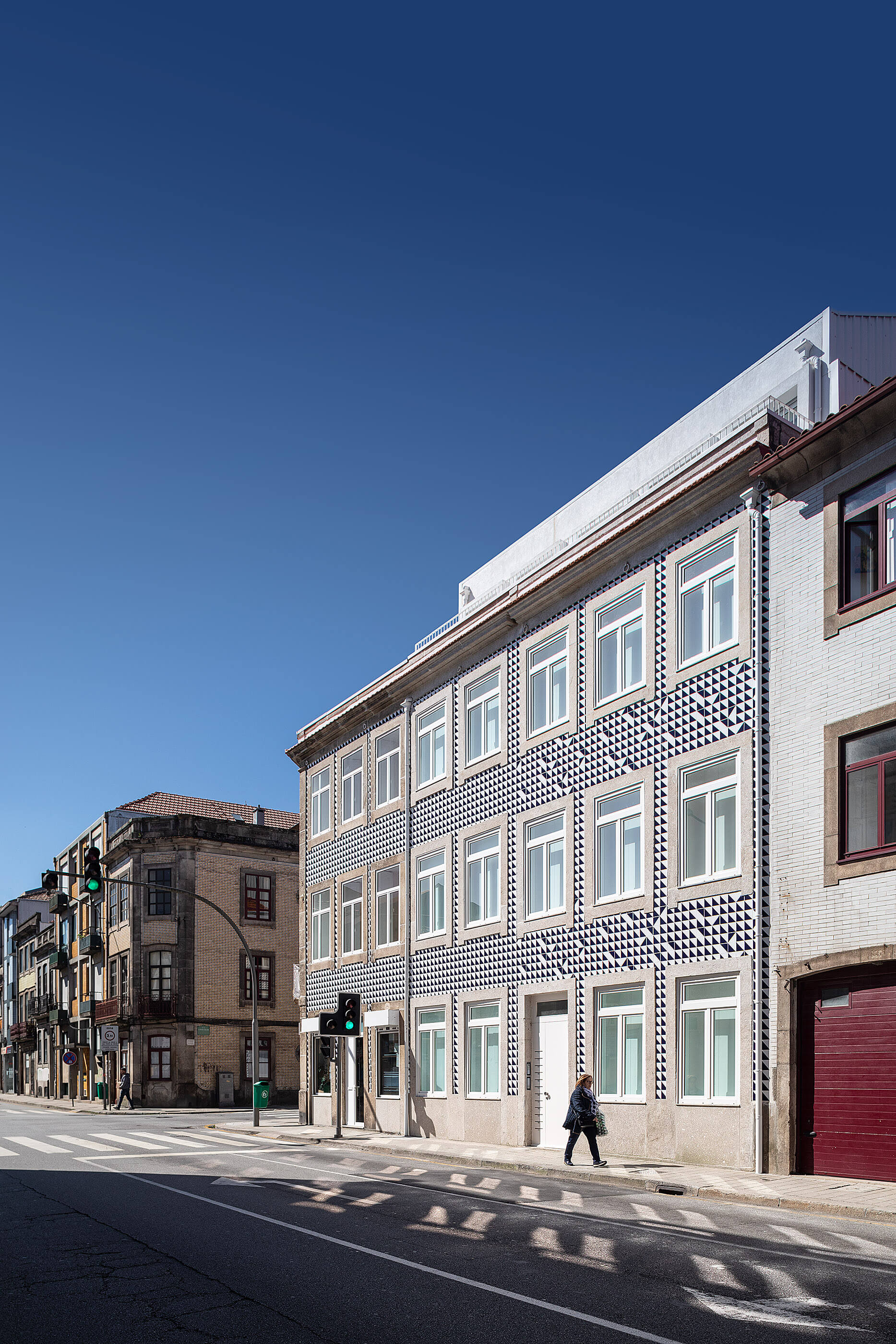 Edifício multifamiliar com fachada revestida a azulejos azuis e brancos, integrado na paisagem urbana do Porto. — Edifício Multifamiliar Alegria arquitetura MiMool Arquitectura & Interiores em Porto