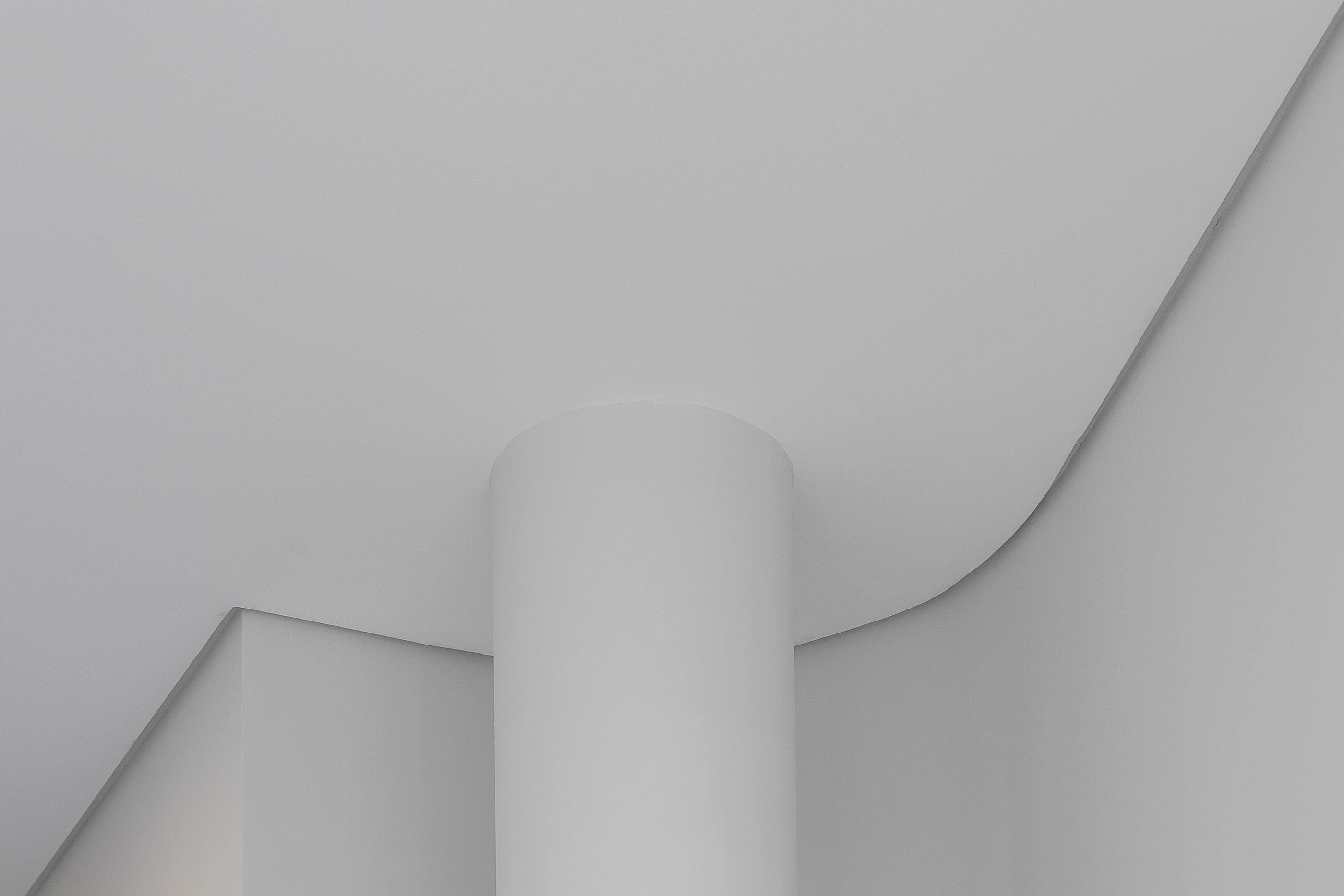 Pormenor arquitetónico do teto branco curvo e coluna cilíndrica, com iluminação indireta. — Clínica de Fisioterapia Mar Saúde arquitetura Hinterland Architecture Studio em Vila Nova de Gaia