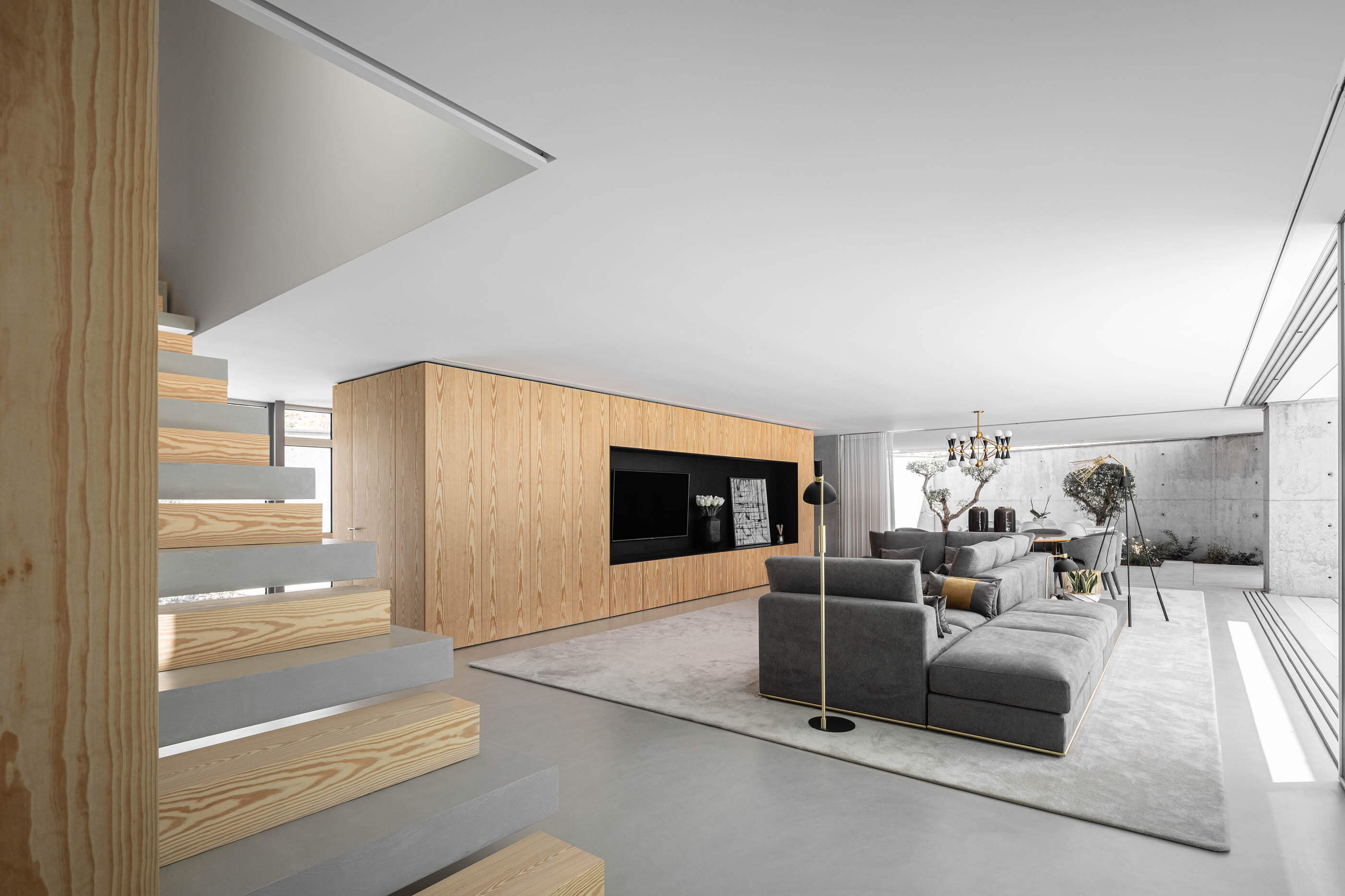Sala de estar e escada da Casa A, com mobiliário moderno e revestimentos em madeira e betão. — Casa A arquitetura REM'A Arquitectos em Portugal