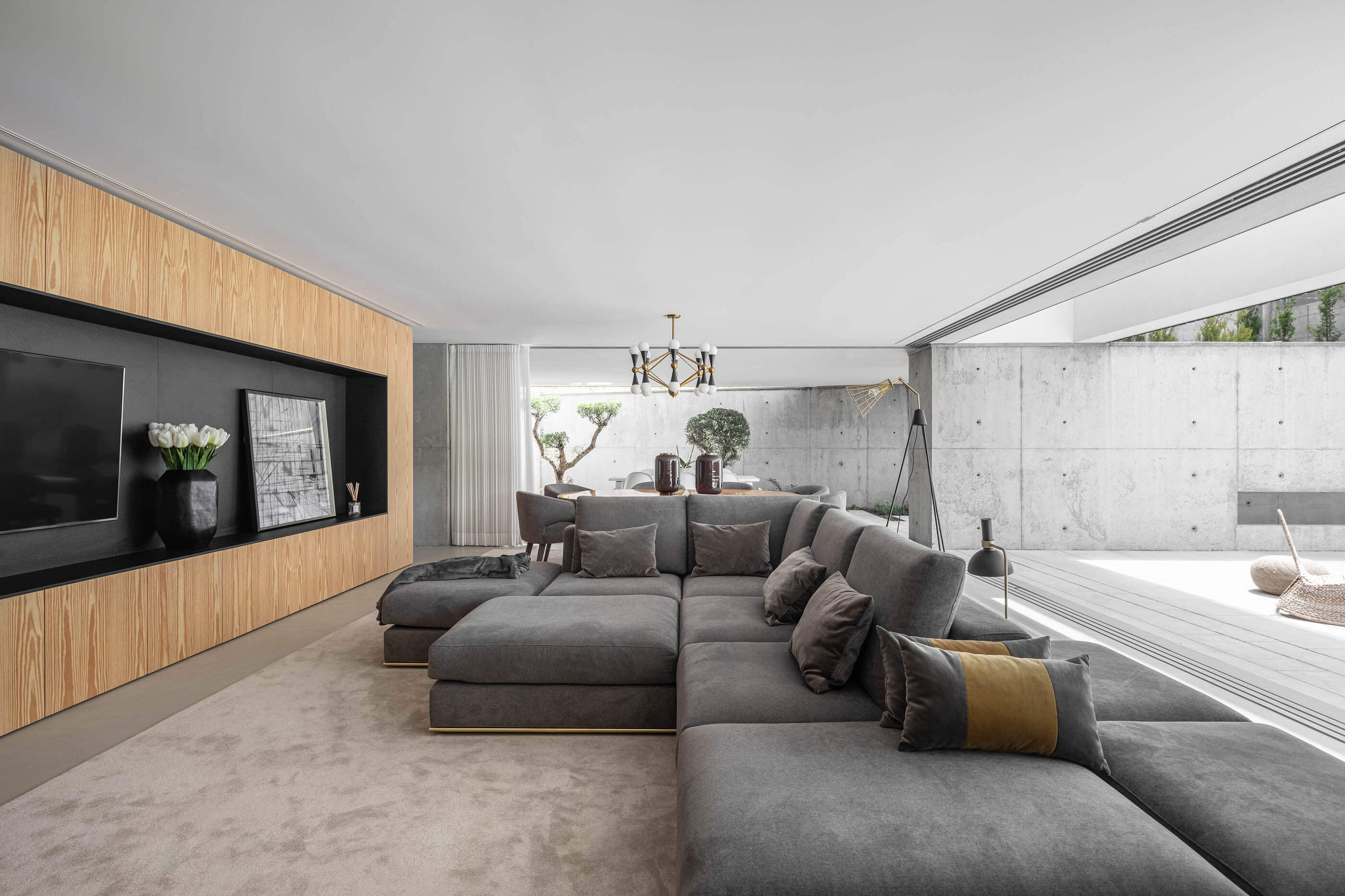 Sala de estar espaçosa com sofá cinzento, tapete claro e parede revestida a madeira. — Casa A arquitetura REM'A Arquitectos em Portugal