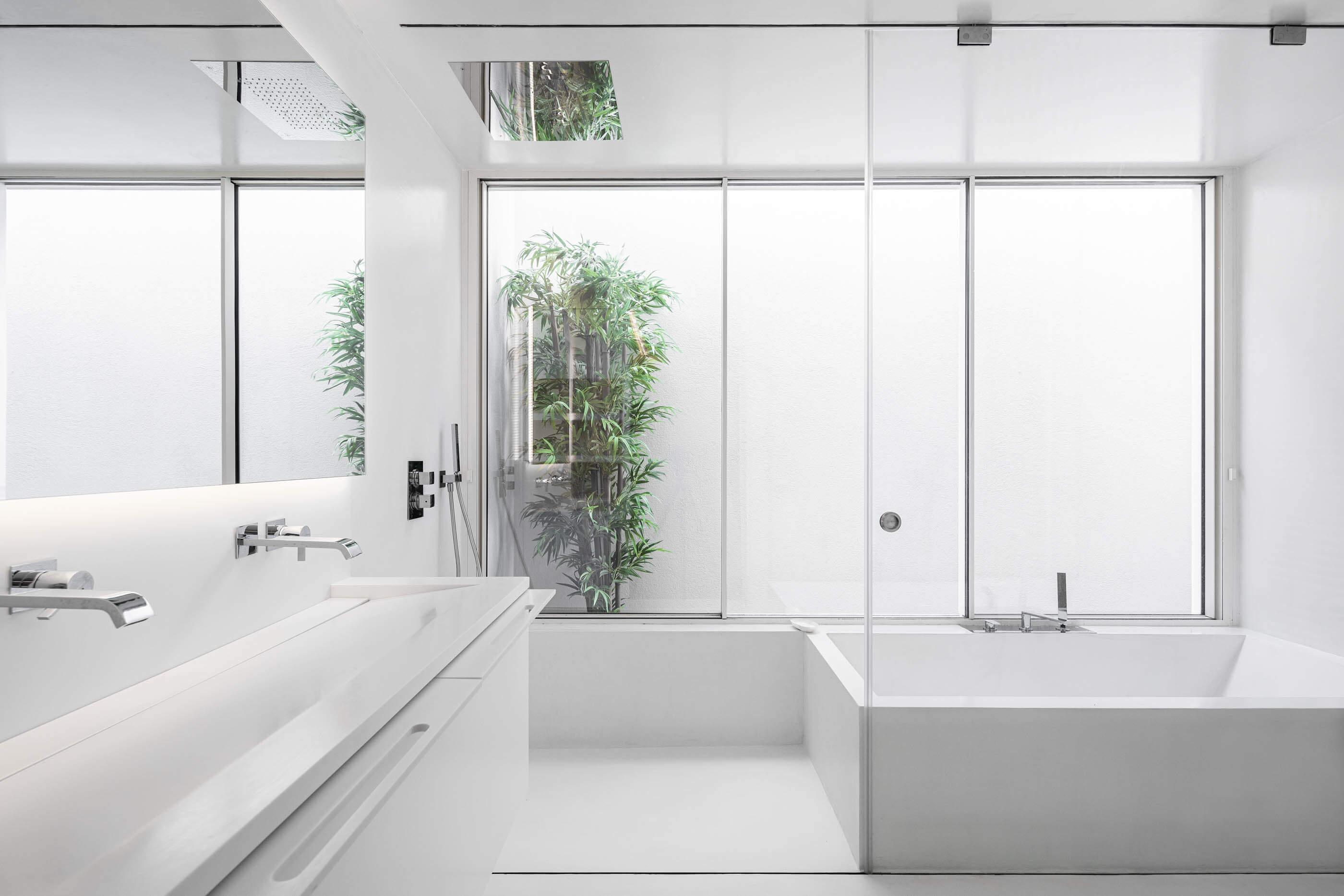 Casa de banho minimalista branca com banheira, duche e janela para um jardim interior. — Casa A arquitetura REM'A Arquitectos em Portugal