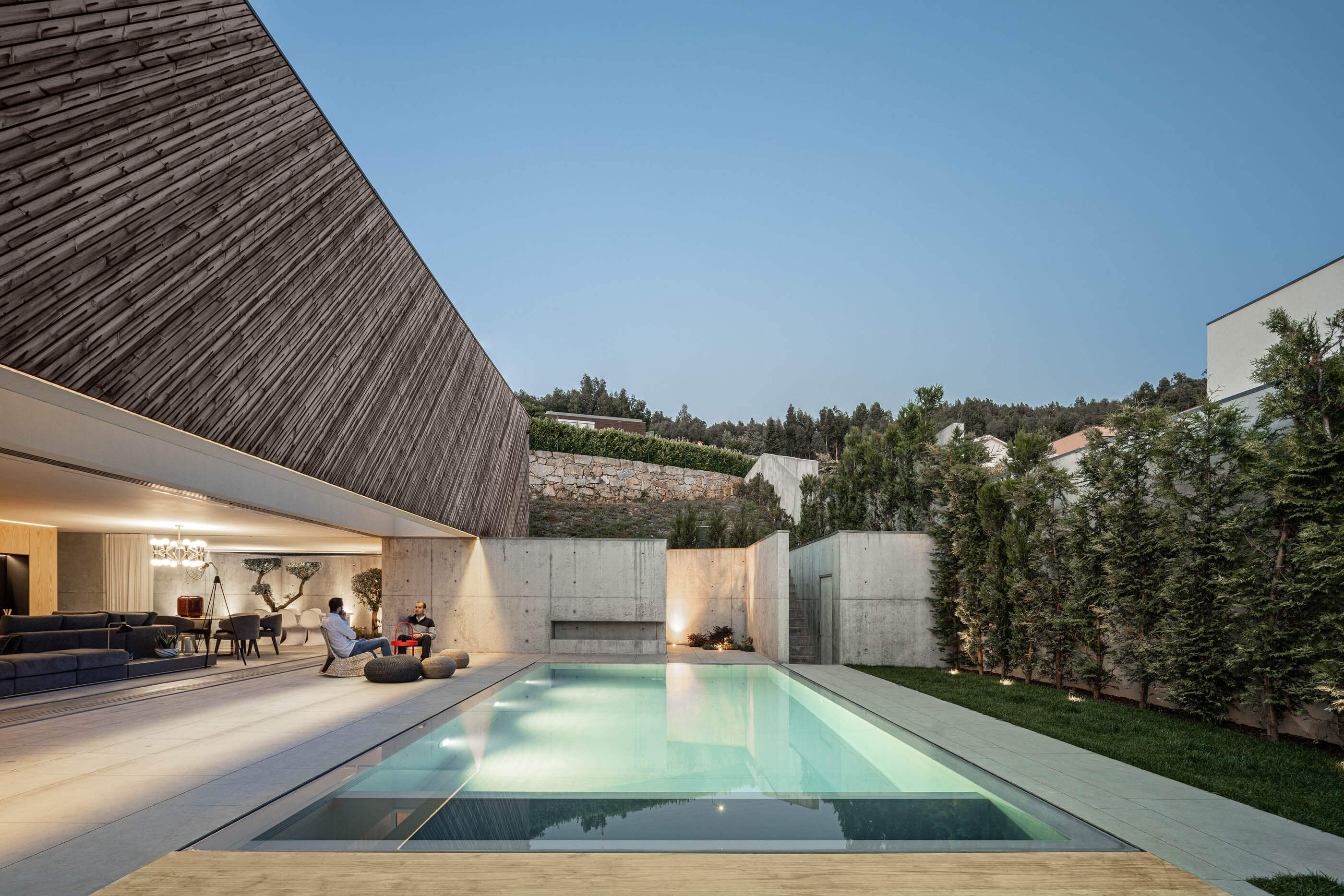 Piscina iluminada da Casa A com zona de estar exterior e vista para a paisagem. — Casa A arquitetura REM'A Arquitectos em Portugal