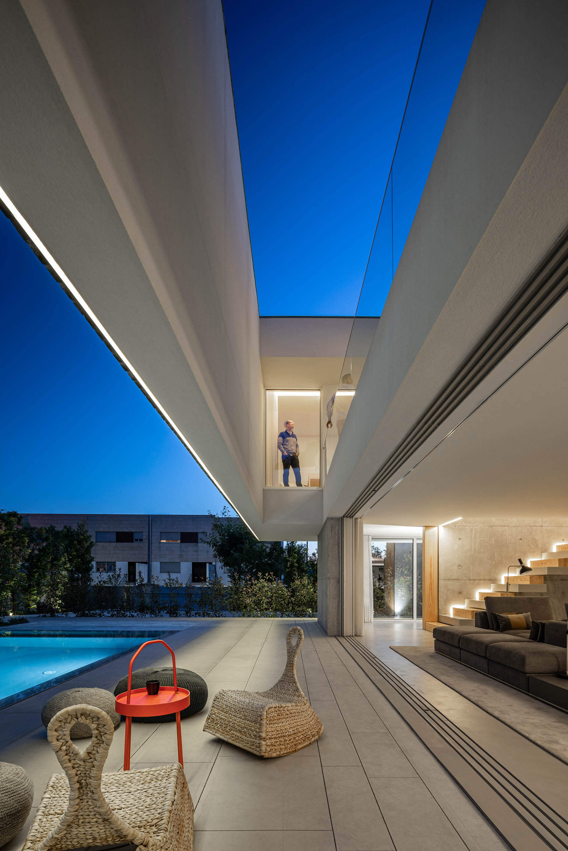 Pátio exterior com piscina, zona de estar e interior da Casa A iluminado à noite. — Casa A arquitetura REM'A Arquitectos em Portugal