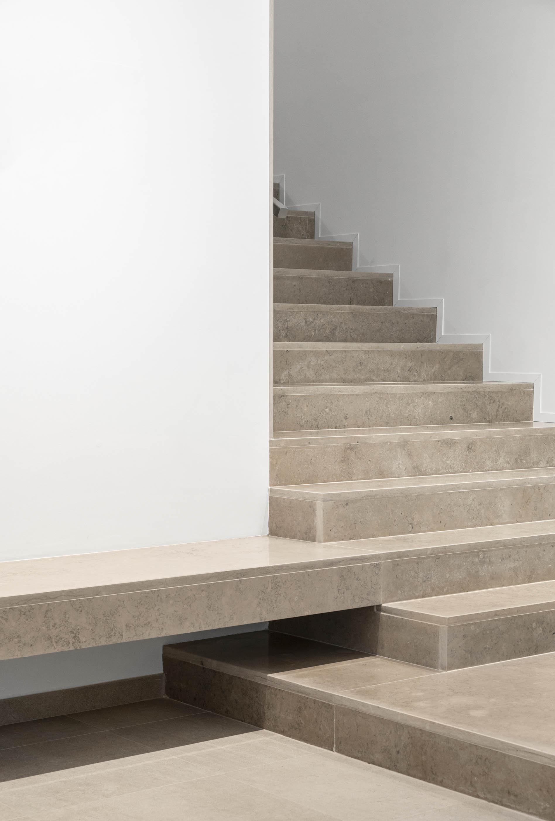 Escadaria interior em pedra clara com paredes brancas, design minimalista e elegante. — Edifício Sede PRF arquitetura Impare Arquitectura em Portugal