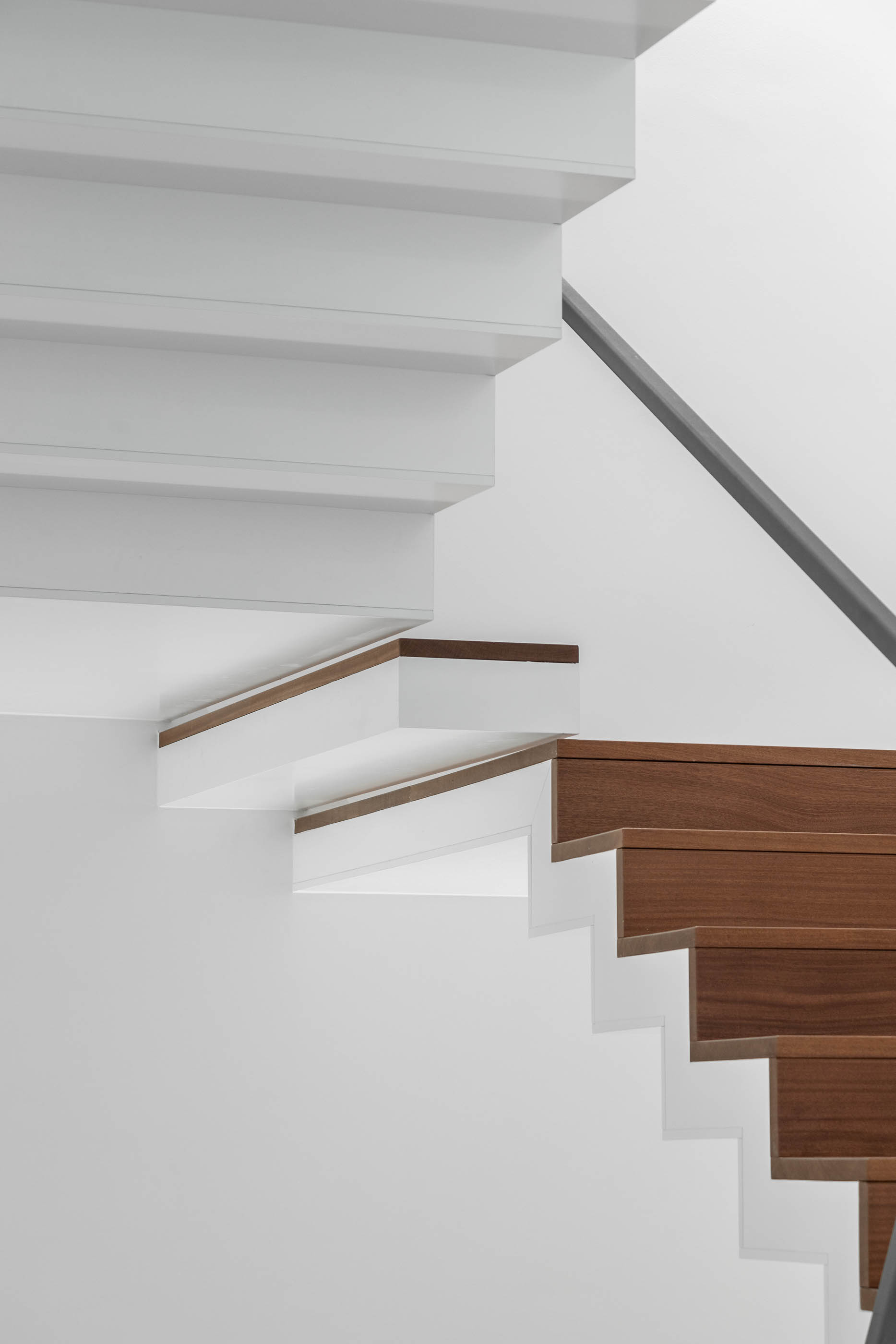 Detalhe de escada com estrutura branca e degraus em madeira, design moderno e minimalista. — Edifício Sede PRF arquitetura Impare Arquitectura em Portugal
