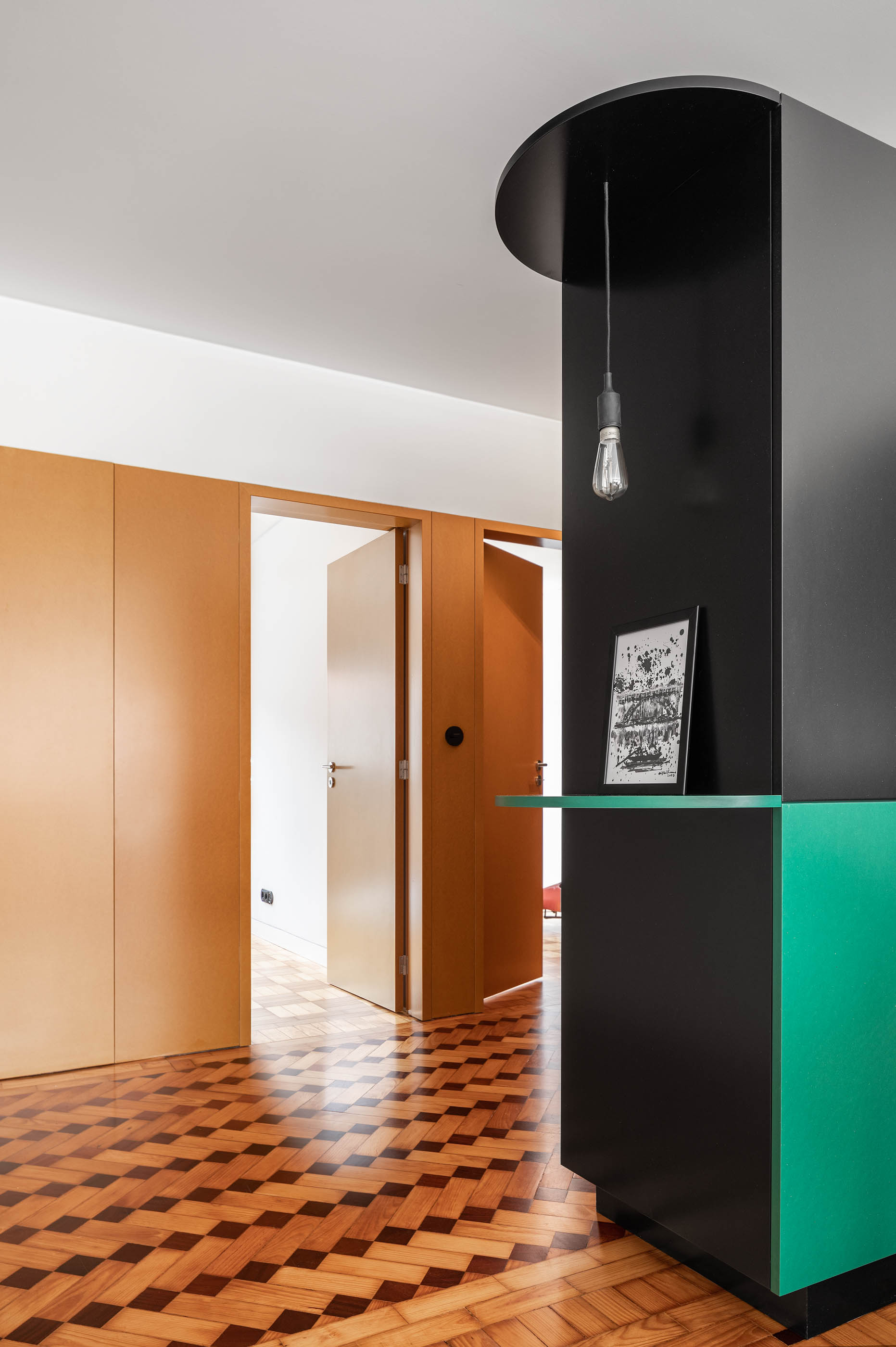 Hall de entrada com armário preto e verde, pavimento em madeira e portas em madeira cor de mel. — Apartamento Morro arquitetura Hinterland Architecture Studio em Vila Nova de Gaia