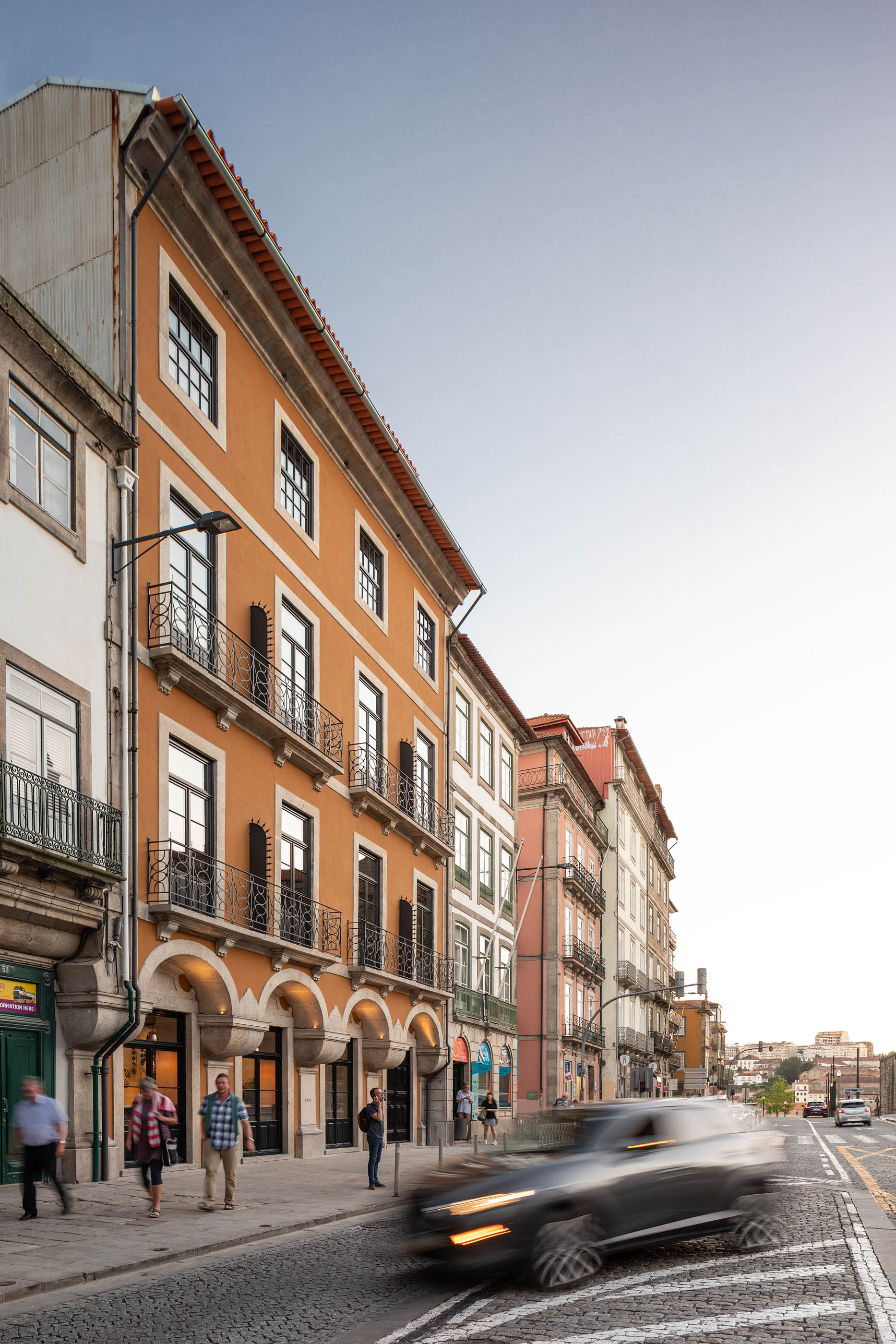 Fachada laranja do hotel com varandas em ferro forjado, integrada na rua histórica do Porto. — Exmo Hotel arquitetura Floret Arquitectura em Porto