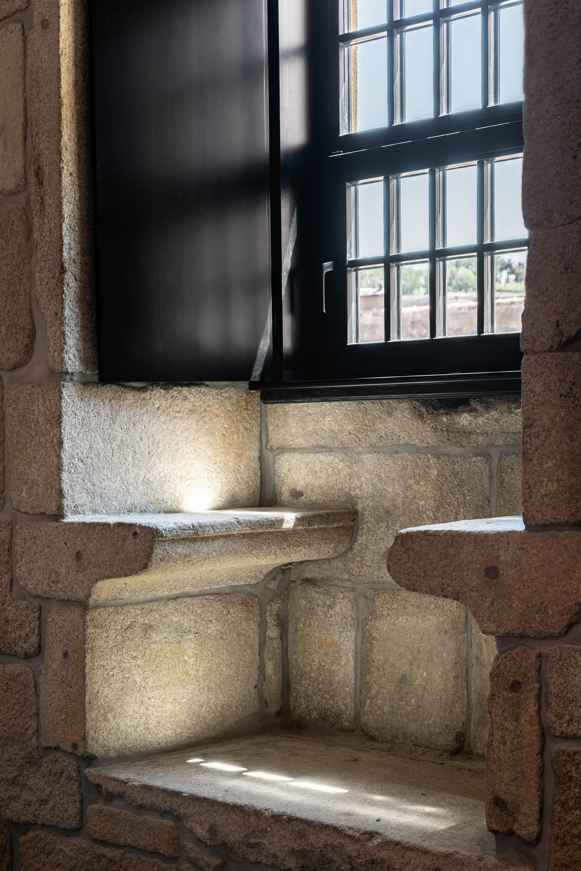 Detalhe da janela com estrutura em pedra original e portadas pretas, evidenciando a história do edifício. — Exmo Hotel arquitetura Floret Arquitectura em Porto