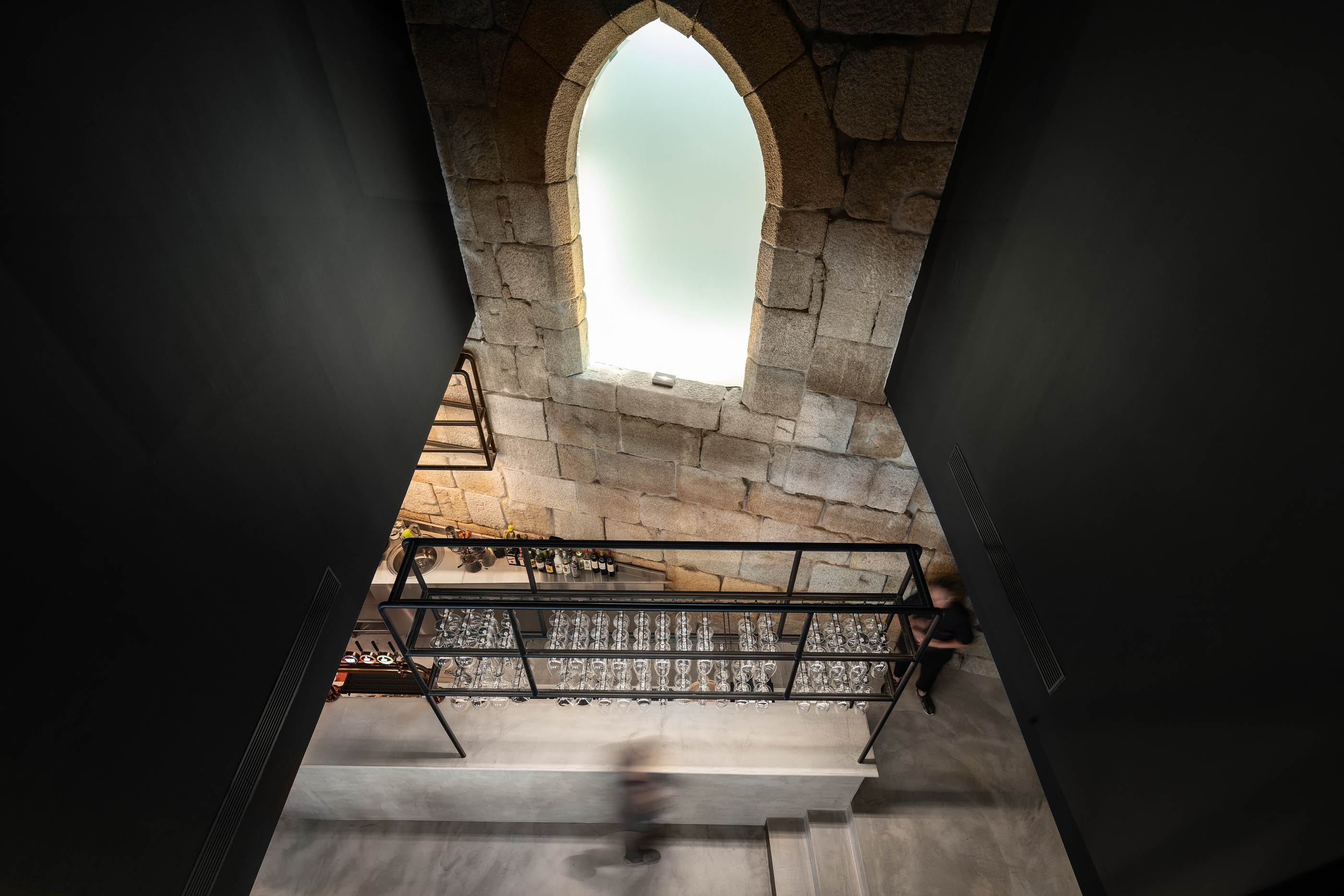 Espaço de bar com estrutura em pedra original e iluminação moderna, criando um ambiente único. — Exmo Hotel arquitetura Floret Arquitectura em Porto