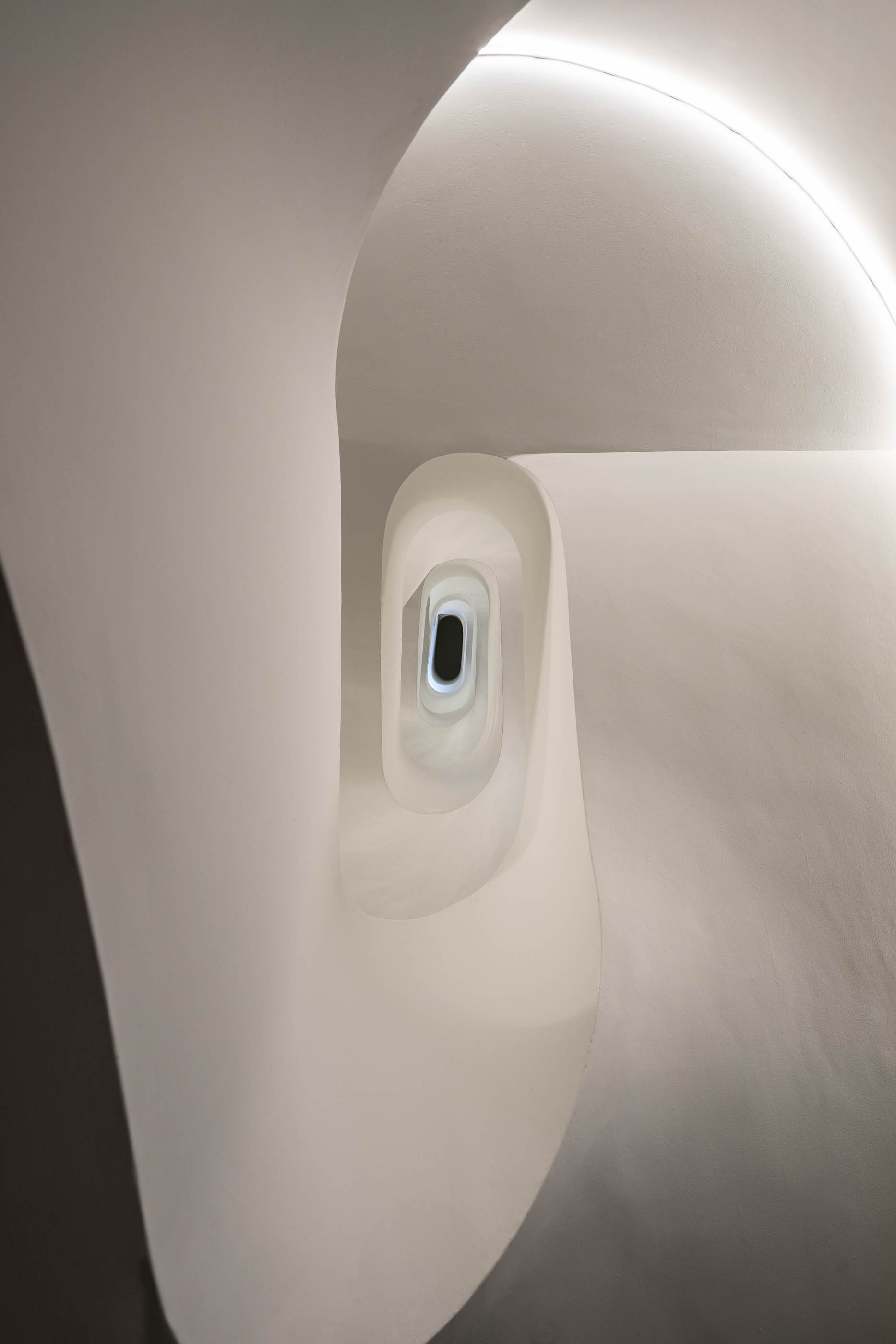 Escadaria em espiral branca com iluminação zenital, design moderno e elegante. — Exmo Hotel arquitetura Floret Arquitectura em Porto