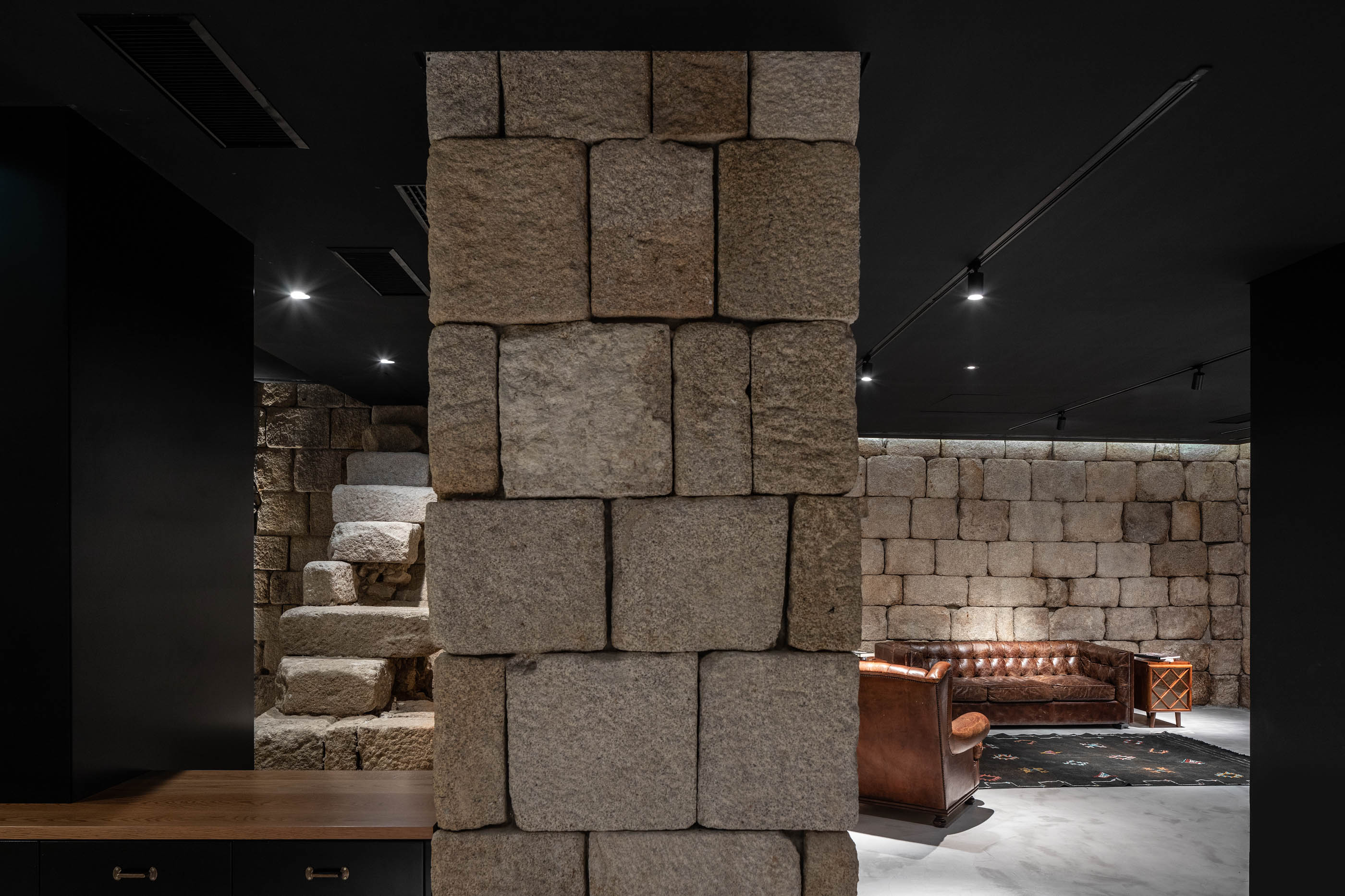 Espaço com paredes em pedra original, escadaria em pedra e mobiliário moderno, contraste de estilos. — Exmo Hotel arquitetura Floret Arquitectura em Porto