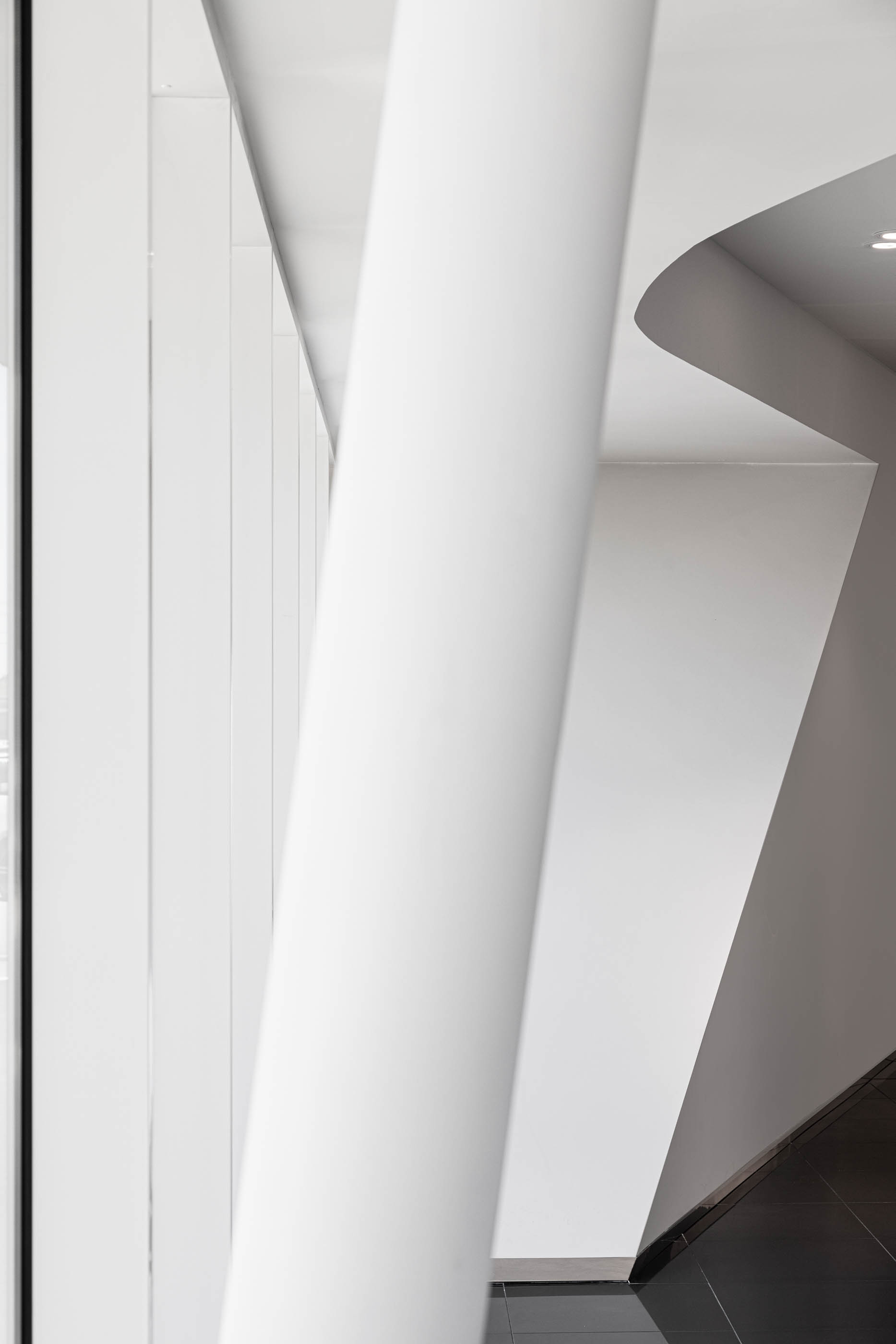 Detalhe arquitetónico do interior do stand Lexus, com pilares brancos inclinados e linhas curvas no teto. — Stand Lexus Faro arquitetura Rarcon Arquitectura em Portugal