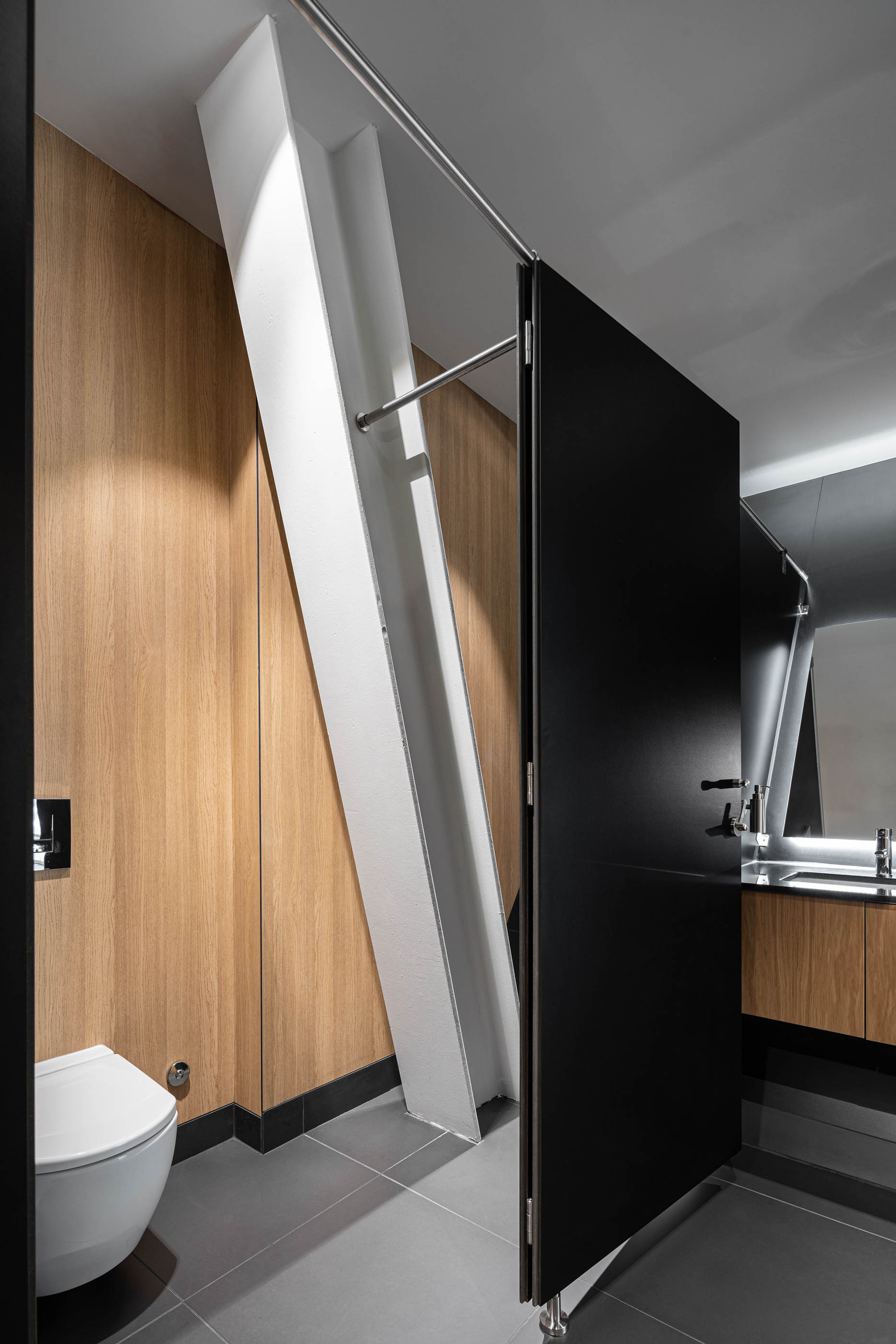 Casa de banho do stand Lexus, com design moderno, paredes em madeira, louças brancas e detalhes em preto. — Stand Lexus Faro arquitetura Rarcon Arquitectura em Portugal