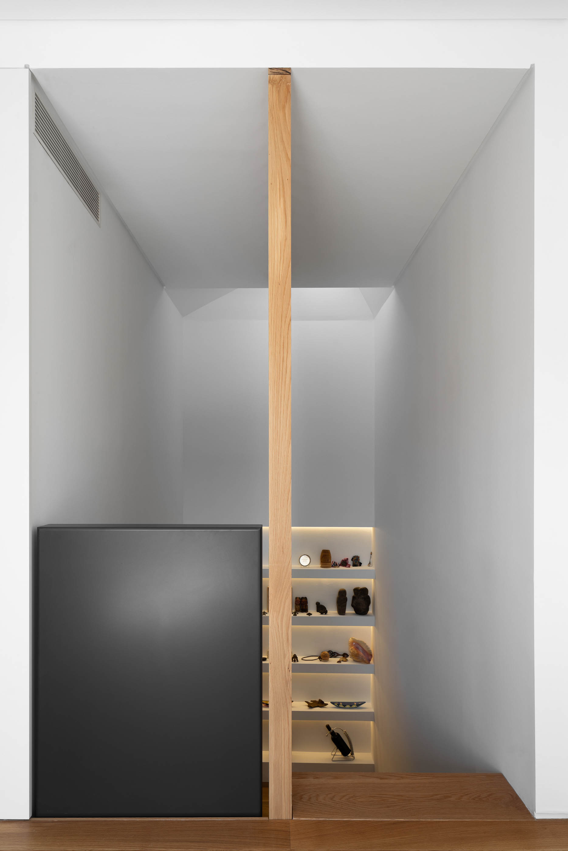 Hall de entrada com armário preto, estante iluminada e escada de madeira. — Casa GD arquitetura Esquissos Arquitectura em Portugal