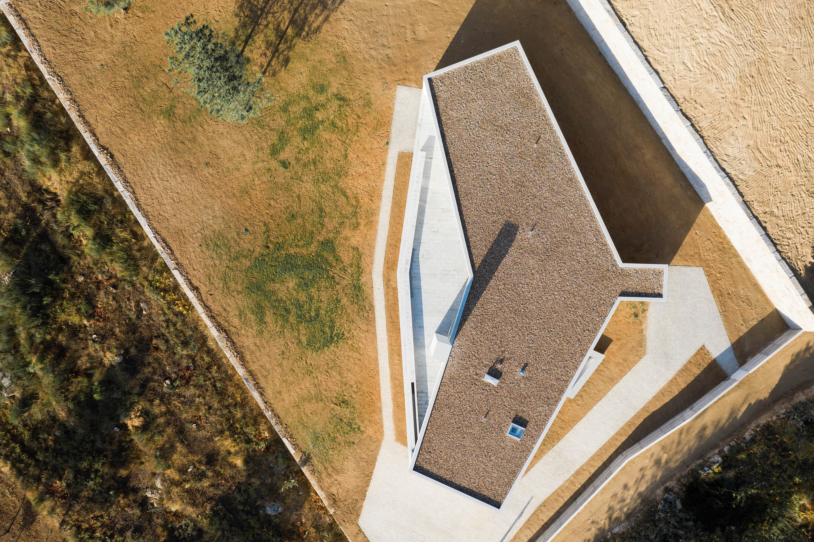 Vista aérea da casa com telhado castanho e envolvente ajardinada, em estilo minimalista. — Casa em Lamego arquitetura António Ildefonso Arquitectura em Portugal