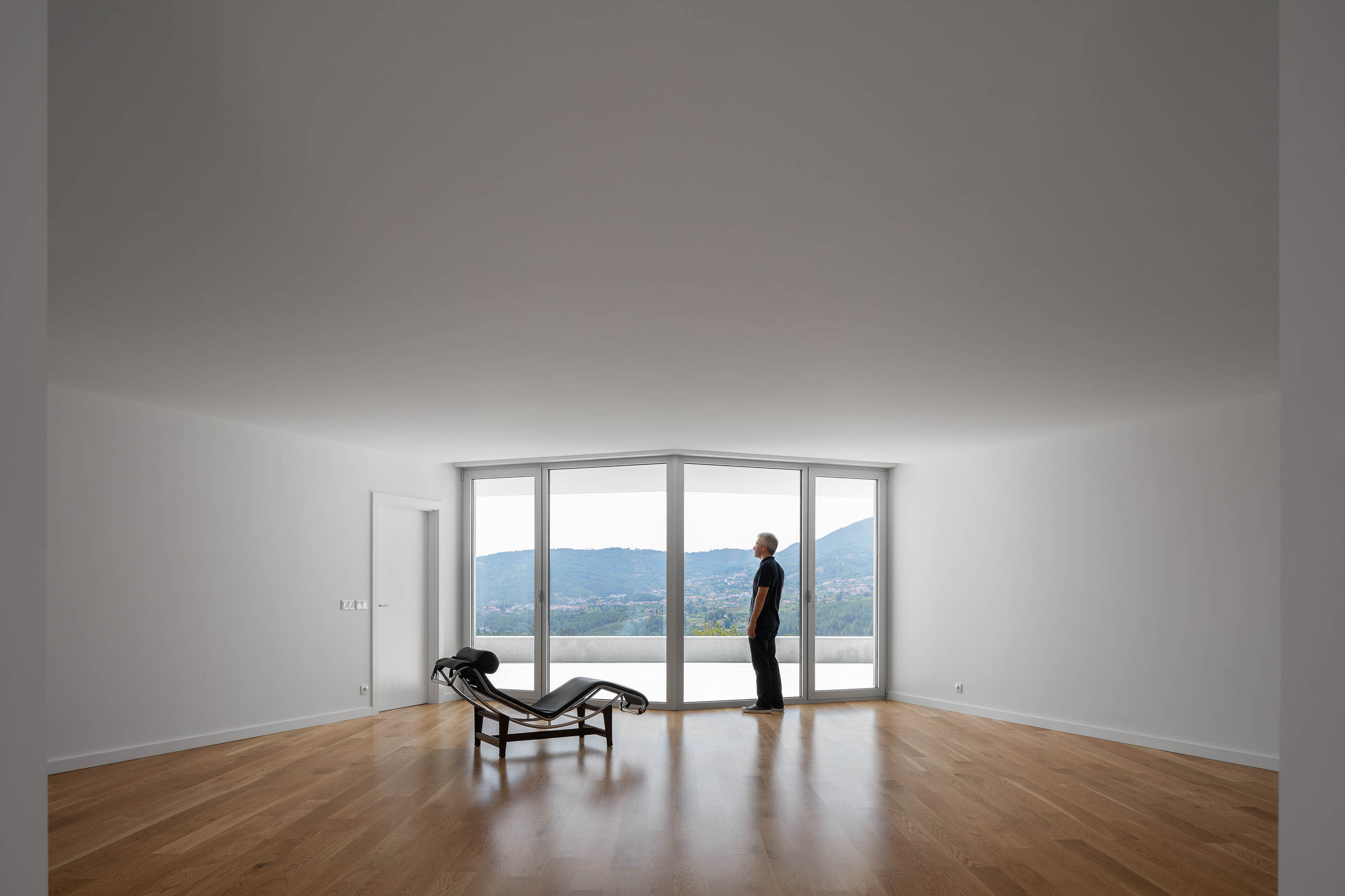 Interior da sala com chão de madeira, chaise longue e vista panorâmica. — Casa em Lamego arquitetura António Ildefonso Arquitectura em Portugal