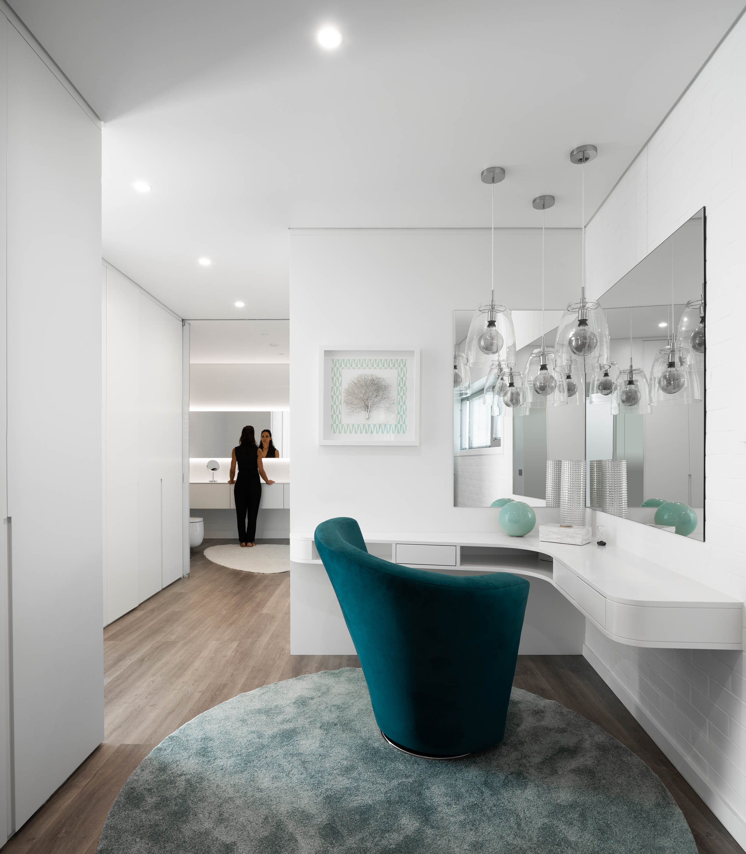 Quarto de vestir com toucador branco, cadeira azul turquesa e espelhos com iluminação suspensa. — Reabilitação Casa J arquitetura Frari em Portugal