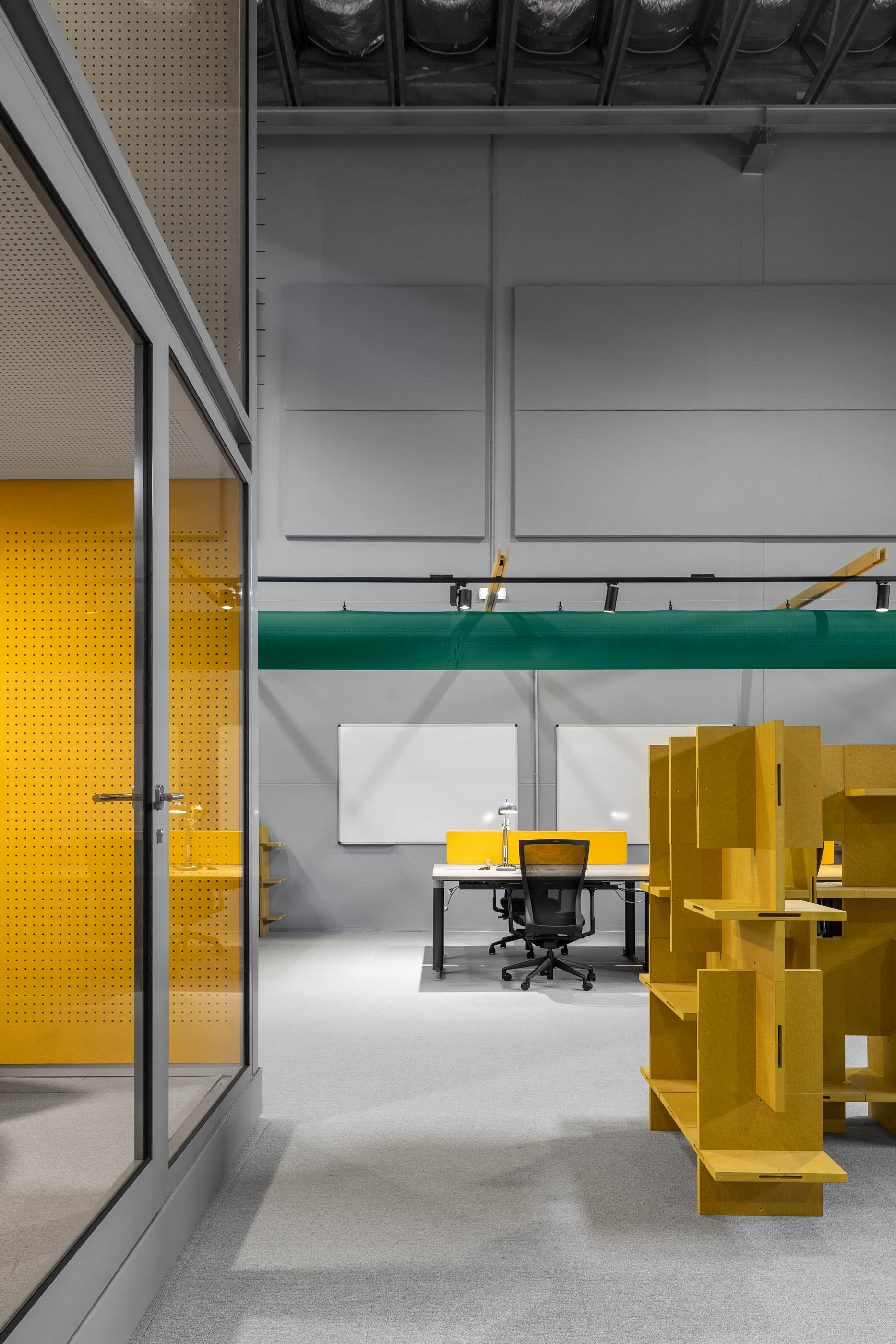 Espaço amplo: Detalhe de um escritório com divisórias amarelas, estantes e uma divisória de vidro. — HBK Spectris Innovation Centre arquitetura Studium Creative Studio em Porto