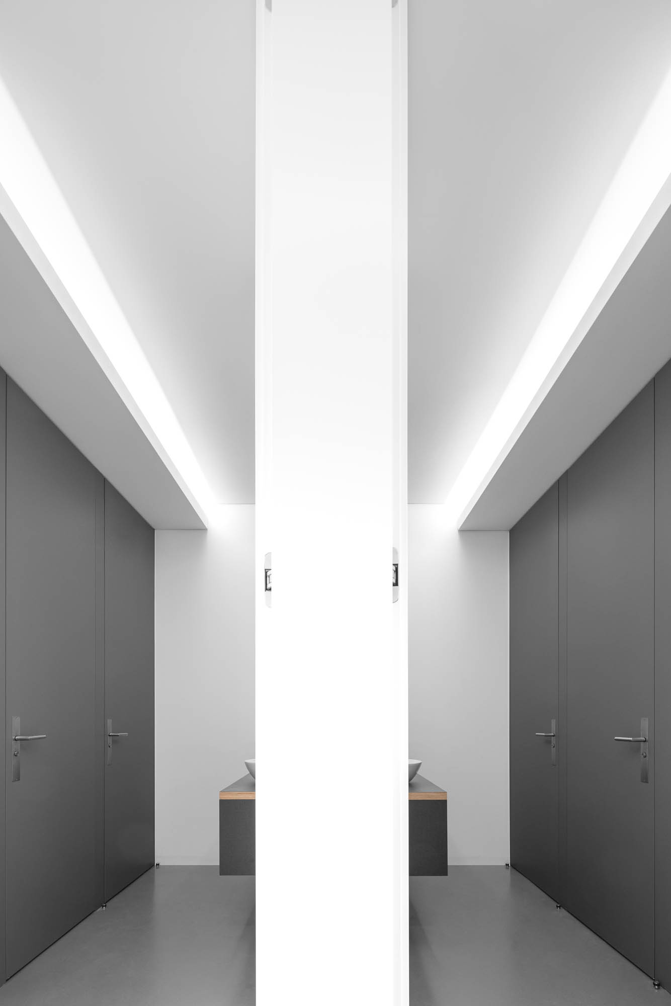 Casa de banho com lavatório de pousar sobre móvel preto, espelho vertical e portas cinzentas em ambos os lados. — Escritórios MA arquitetura éOp – arquitectura e design em Maia