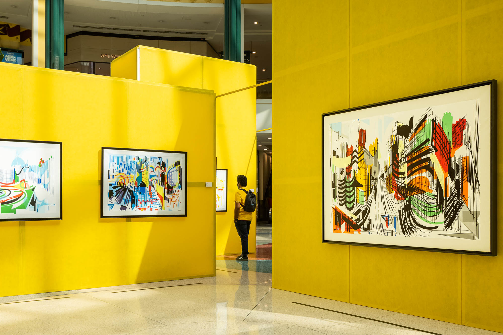 Divisão com painéis amarelos, exibindo obras de Nadir Afonso com visitantes a observar as pinturas. — Museu Temporário Nadir Afonso arquitetura Diogo Aguiar Studio em Lisboa