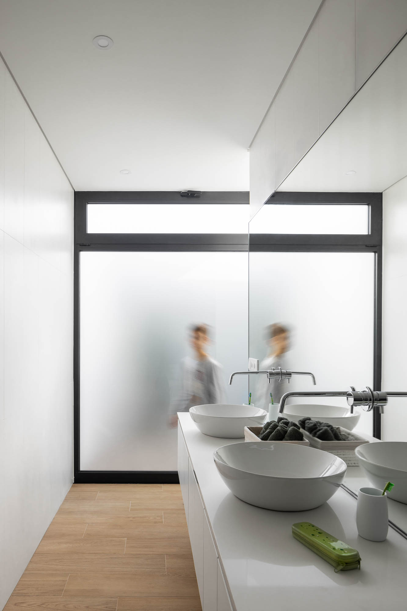 Casa de banho minimalista com lavatório duplo, espelho amplo e janela com vidro fosco. — Casa Diagonal arquitetura Frari em Aveiro