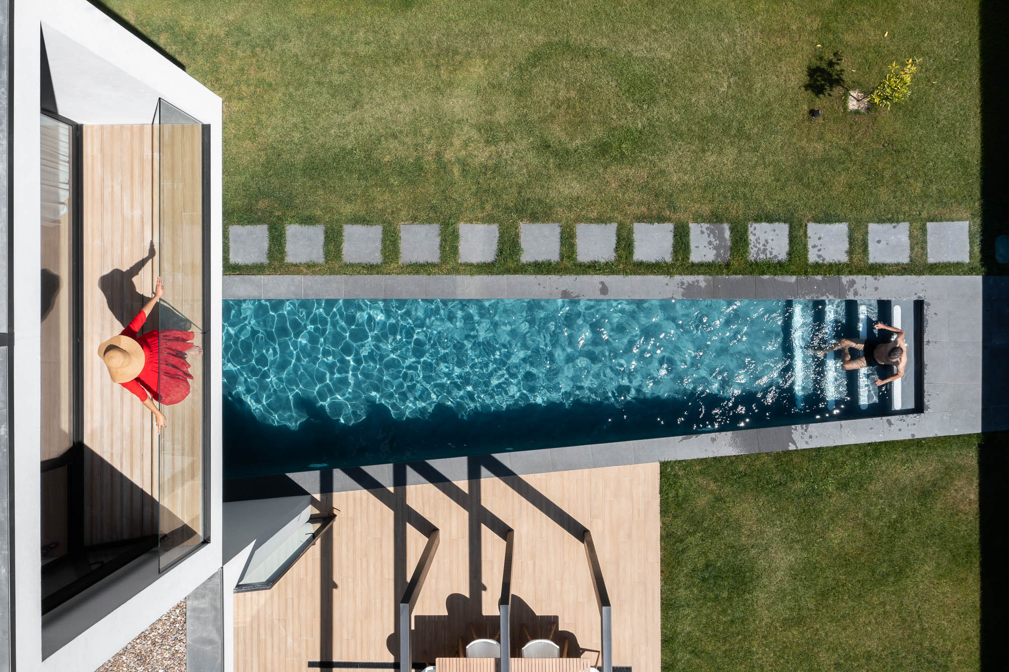 Vista aérea da casa com piscina, relvado, pérgola e varanda com pessoa a observar. — Casa Diagonal arquitetura Frari em Aveiro