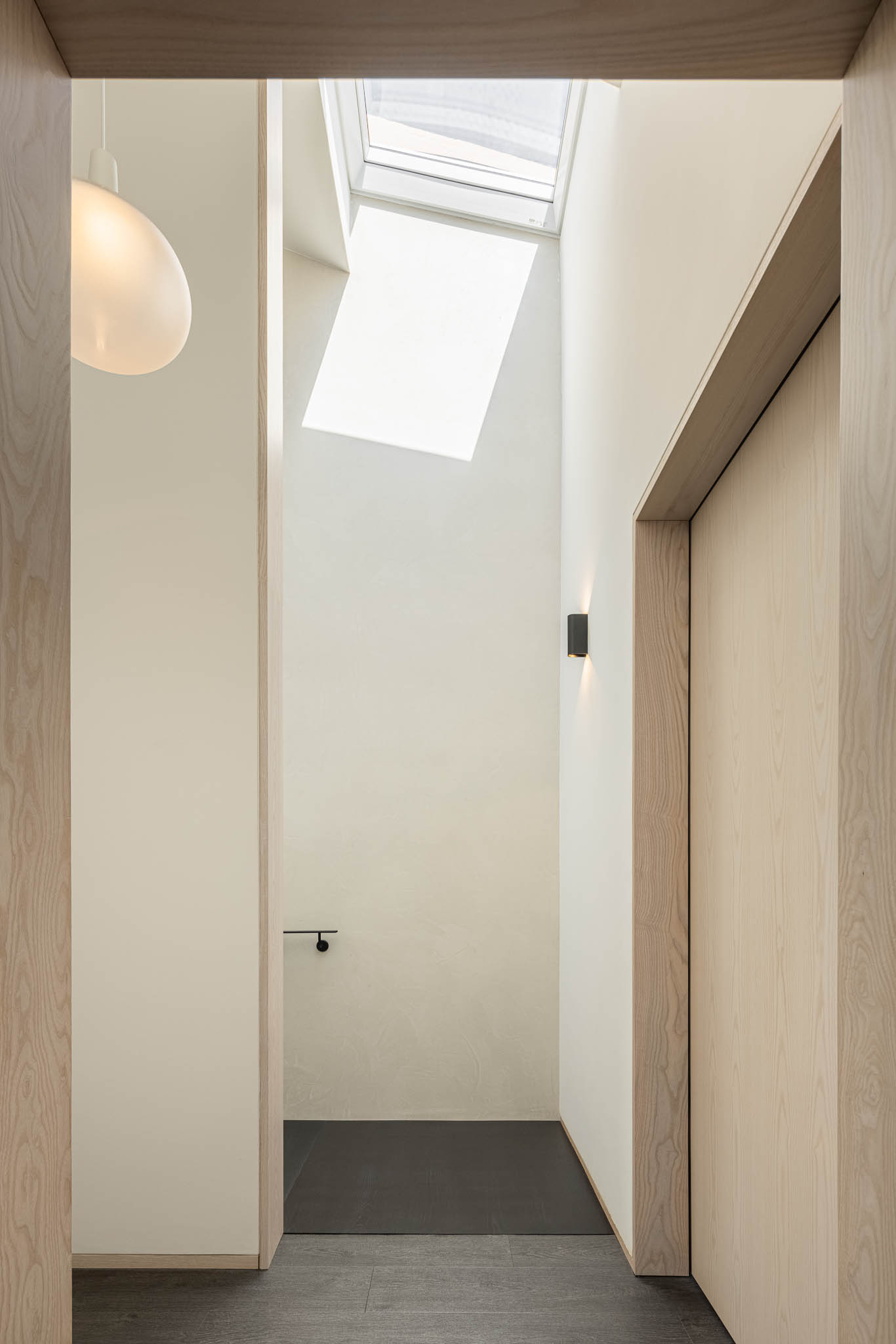Hall de entrada com claraboia, paredes brancas e portas de madeira clara. Iluminação minimalista. — Casa moinho de vento arquitetura BOX arquitectos em Ponta Delgada