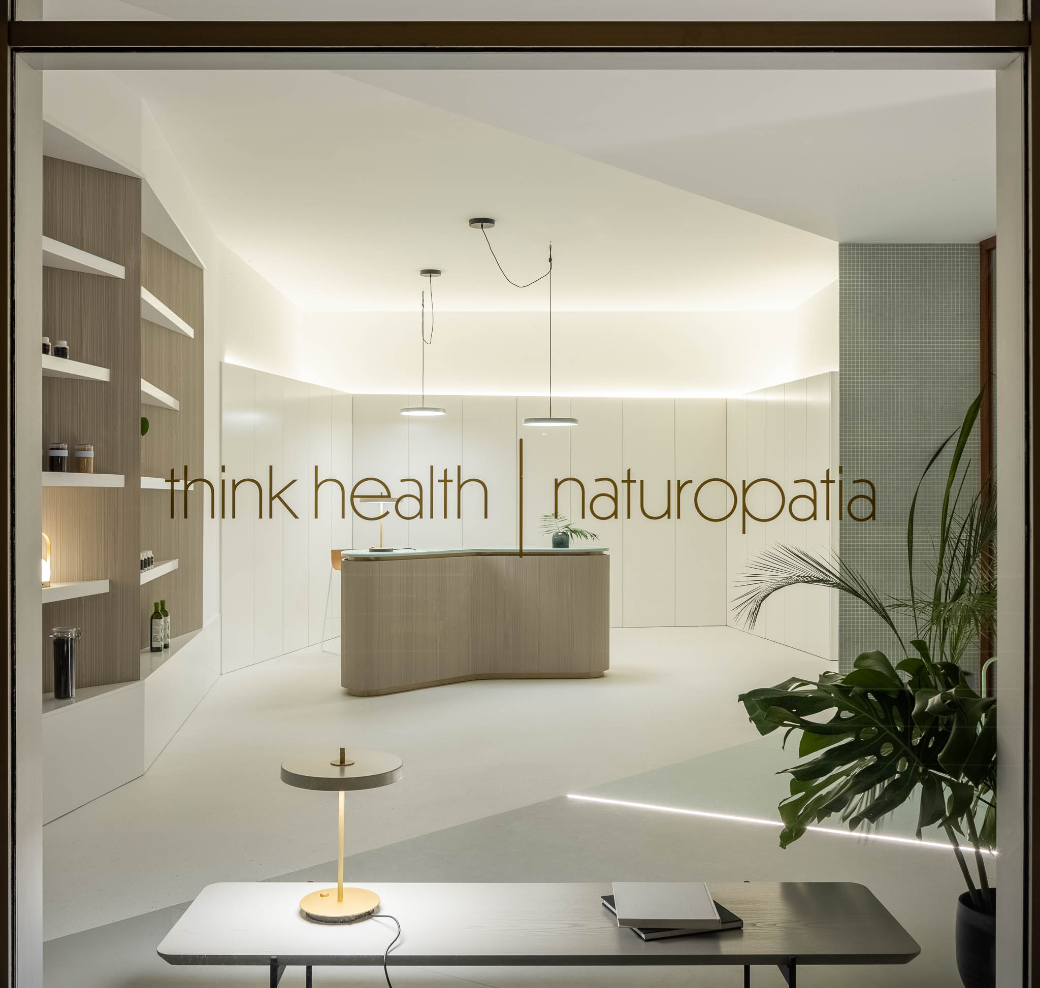 Fachada da clínica com logótipo "think health | naturopatia", balcão de receção e estante visíveis através da montra, convidando à entrada. — Think Health Naturopatia arquitetura BOX arquitectos em Ponta Delgada