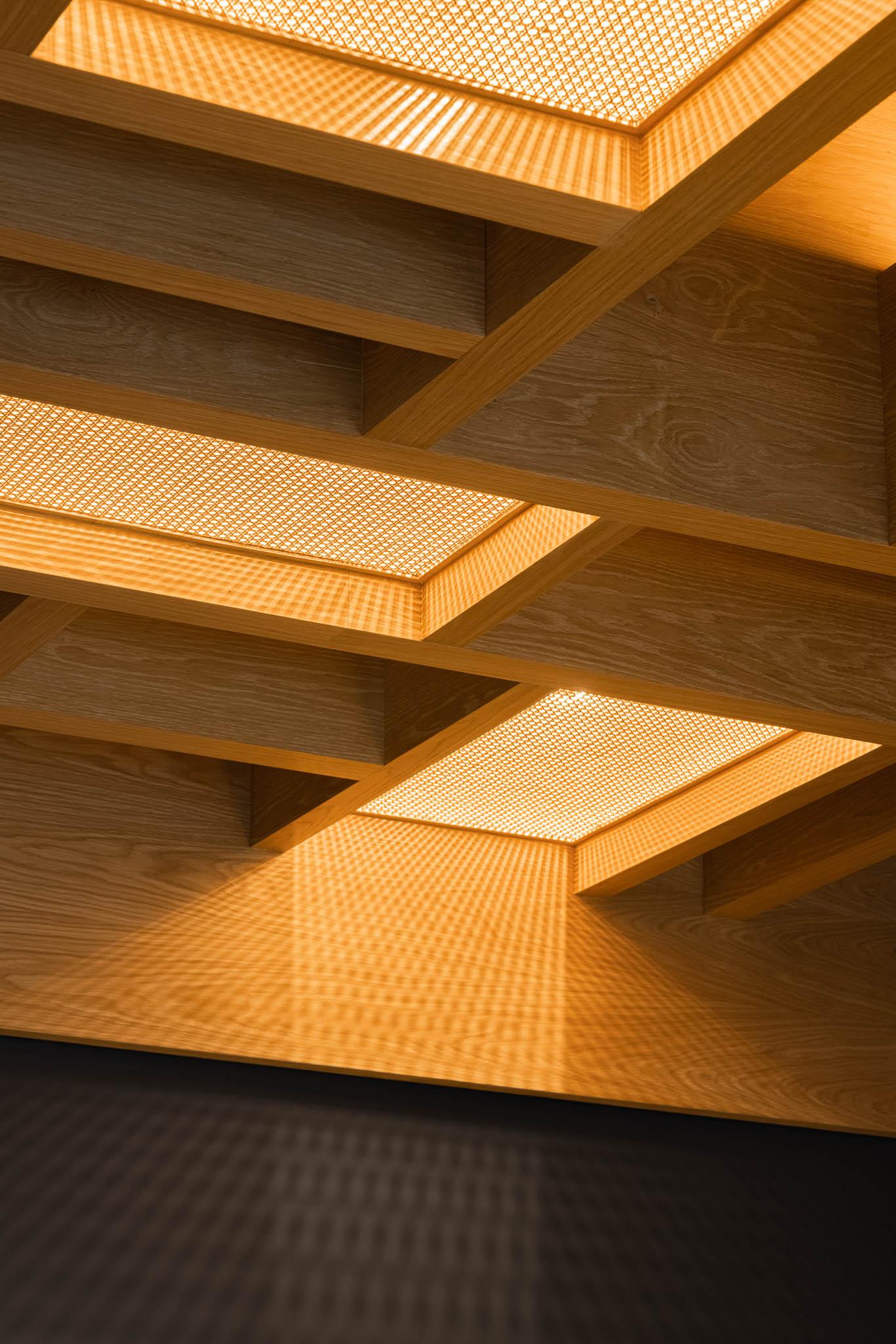 Teto em madeira com padrão geométrico e detalhes em ráfia iluminada, criando um ambiente acolhedor e sofisticado. — Restaurante Fuji arquitetura Sequeira Dias Arquitectos em Ponta Delgada