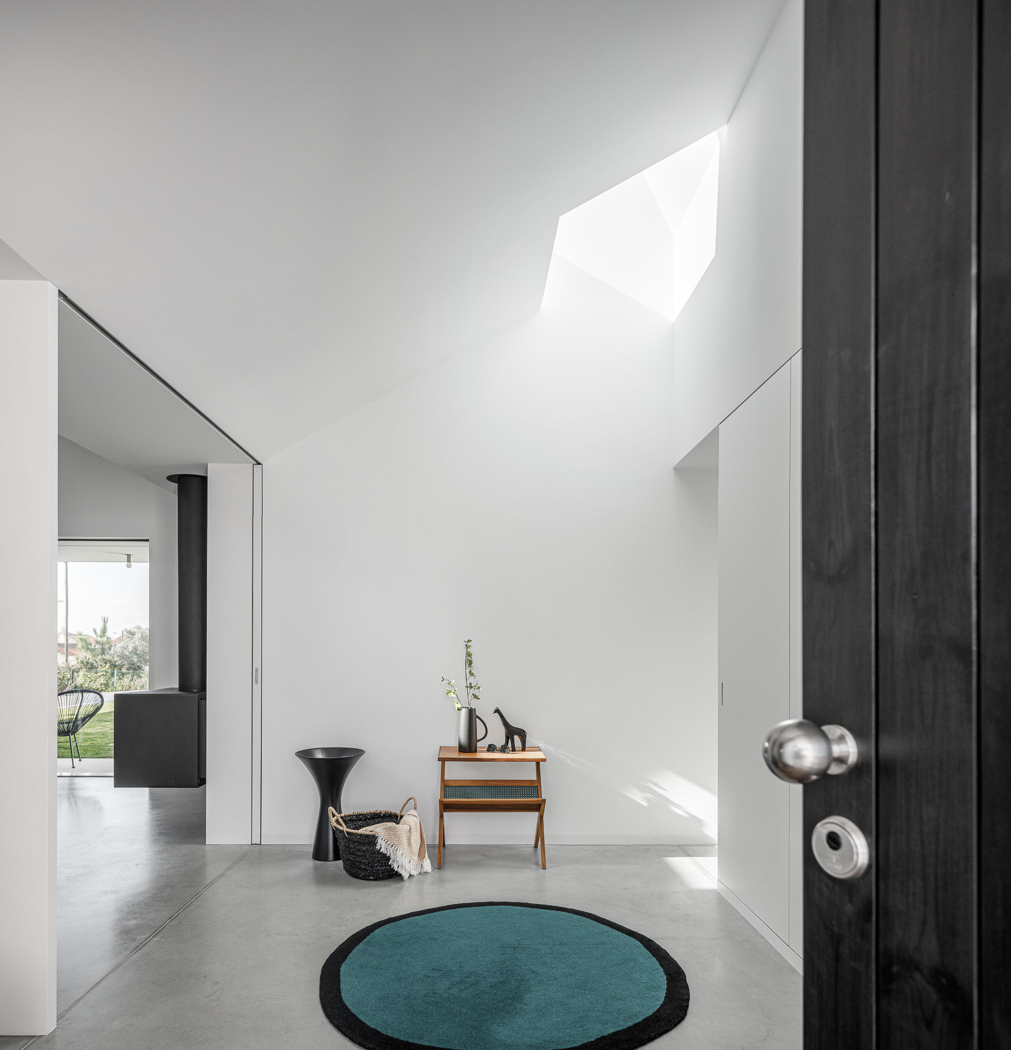 Hall de entrada com luz zenital, pavimento em betão polido e detalhes minimalistas em madeira escura. — Habitação em Santa Joana arquitetura Nu.ma em Aveiro