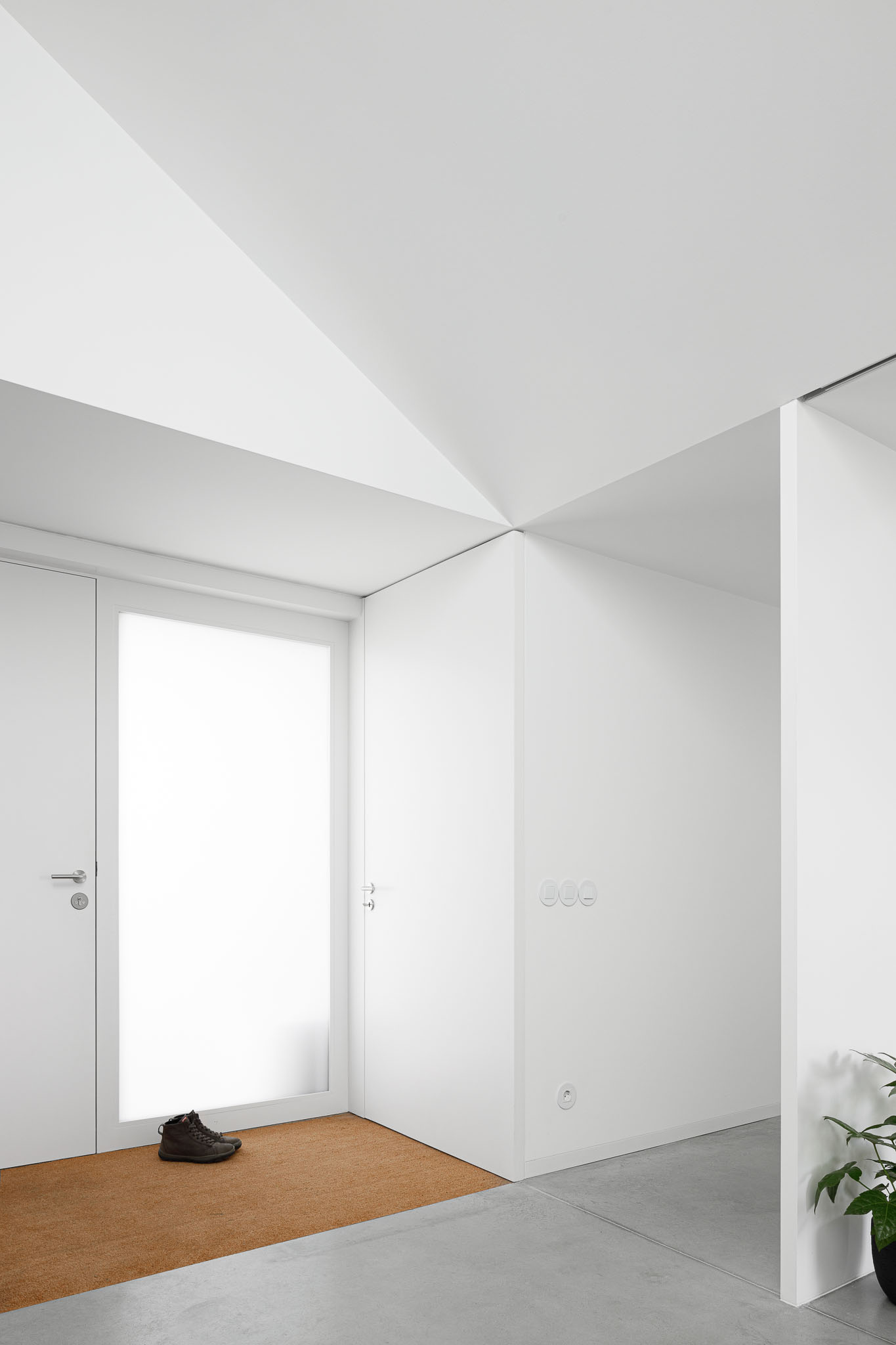 Hall de entrada com teto geométrico, porta branca translúcida e pavimento em betão cinzento. — Habitação em Santa Joana arquitetura Nu.ma em Aveiro