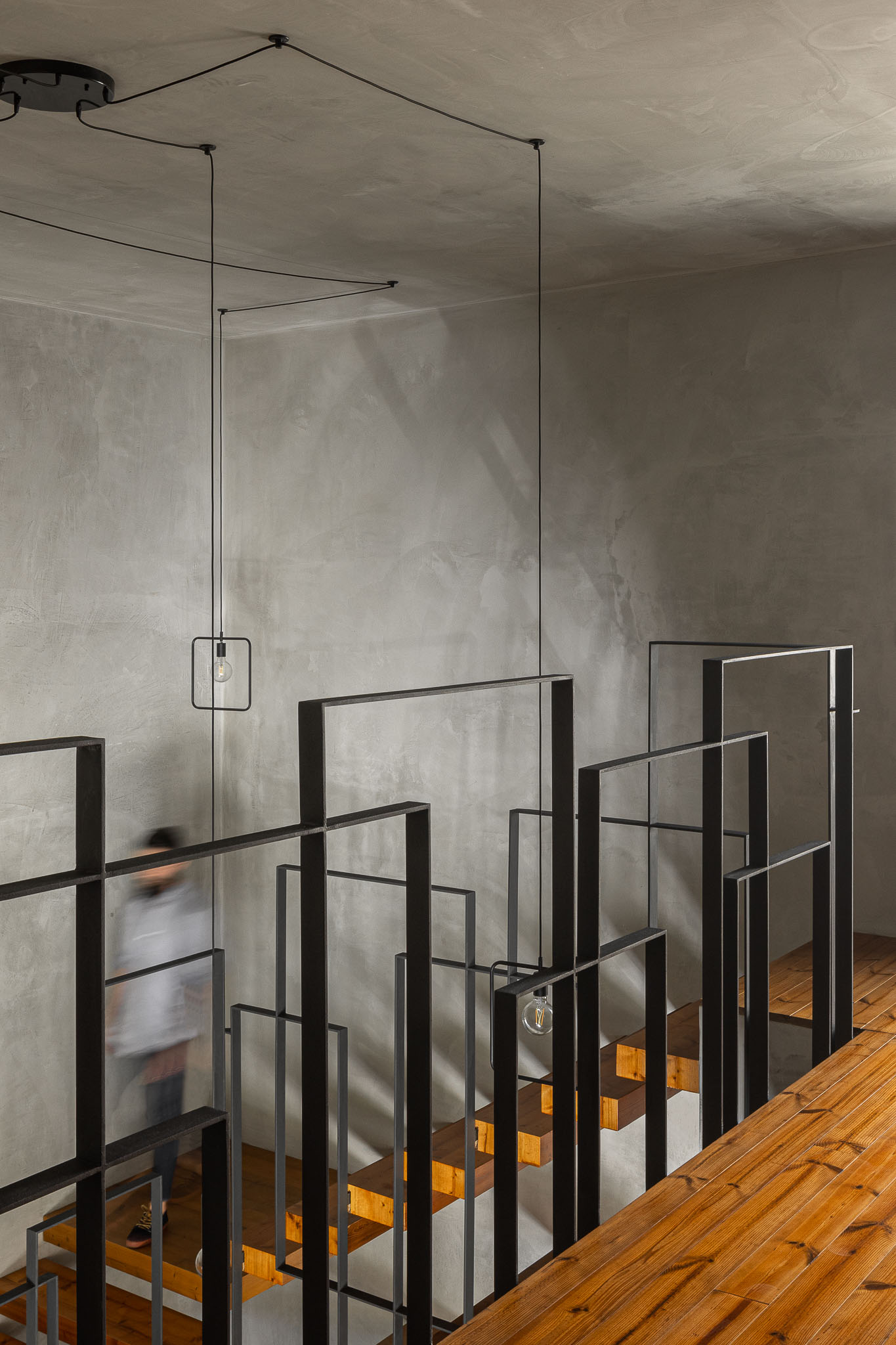 Escadas interiores com estrutura metálica preta e degraus em madeira, iluminação suspensa minimalista. — Casa 15 arquitetura AM-arqstudio em Braga