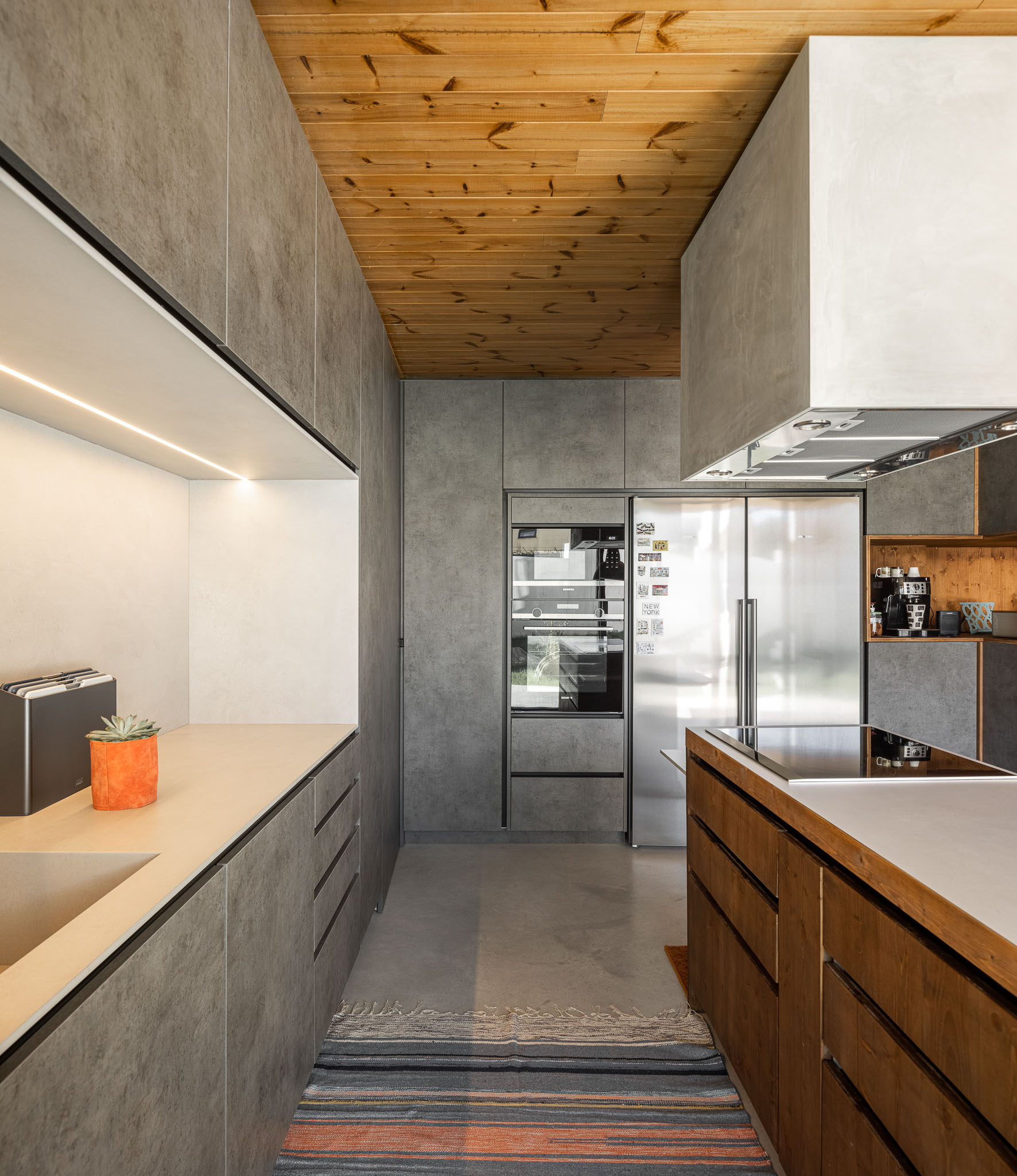 Cozinha com armários cinzentos, bancada em madeira e eletrodomésticos em aço inoxidável. — Casa 15 arquitetura AM-arqstudio em Braga