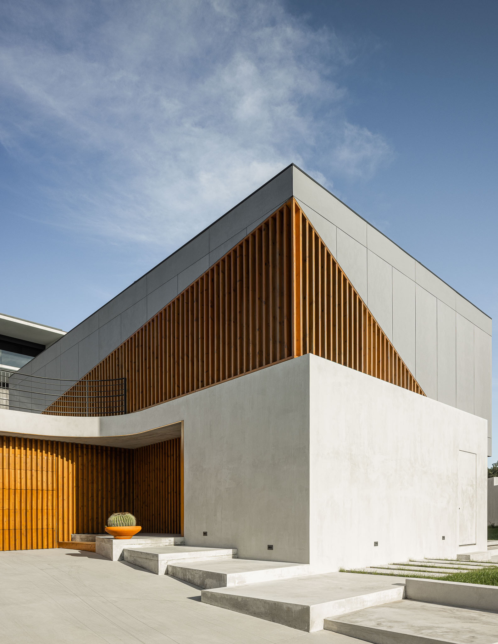 Fachada da casa com revestimento cinzento e detalhes em madeira, escadas de acesso em betão. — Casa 15 arquitetura AM-arqstudio em Braga