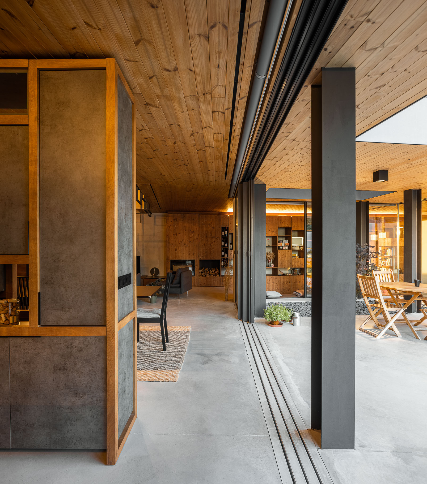 Espaço interior com vista para a sala de estar e zona de refeições exterior, portas de correr envidraçadas. — Casa 15 arquitetura AM-arqstudio em Braga