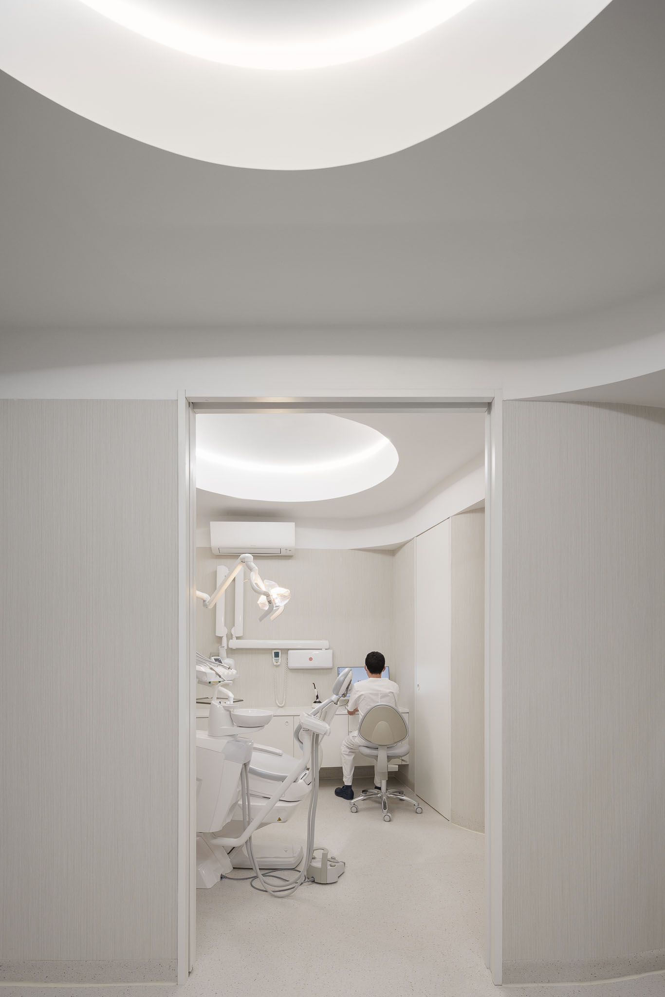 Consultório dentário com equipamento moderno, paredes brancas e iluminação focalizada. — MOOD Medicina Dentária arquitetura Tsou Arquitectos em Maia