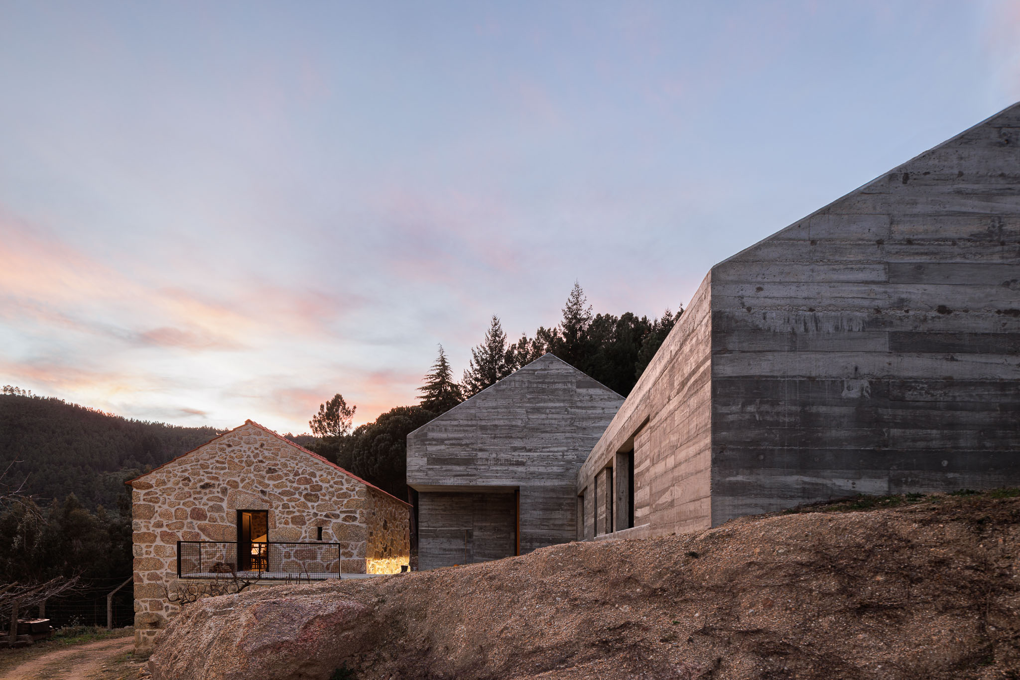 Casa NaMora: Vista noturna da casa com anexo em pedra iluminado e estrutura em betão, sob um céu estrelado. — Casa NaMora arquitetura David Bilo Arquitectos e Filipe Pina Arquitectura em Guarda