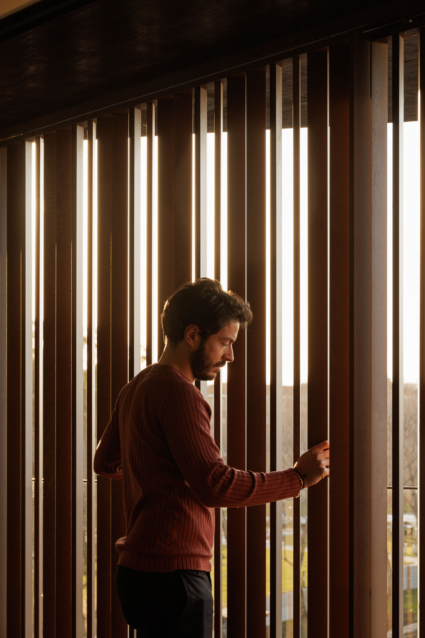 Homem junto a painéis verticais de madeira, com luz natural filtrada e ambiente acolhedor. — Puro Homes arquitetura Mário Alves Arquitecto em Aveiro
