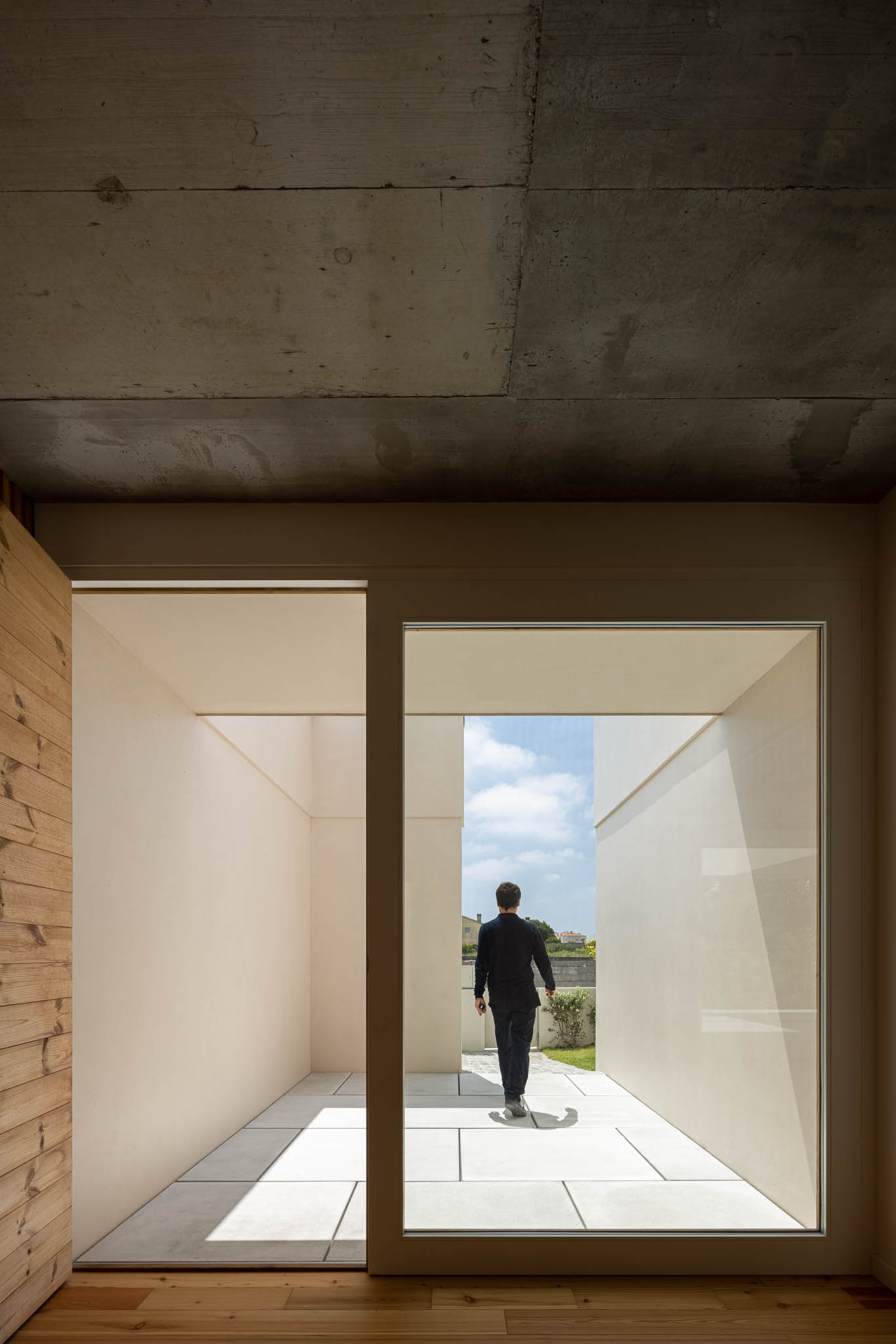 Pátio: Espaço exterior com pavimento cerâmico, paredes brancas e teto em betão aparente. — Casa em Ílhavo arquitetura M2Senos Arquitectos em Ílhavo