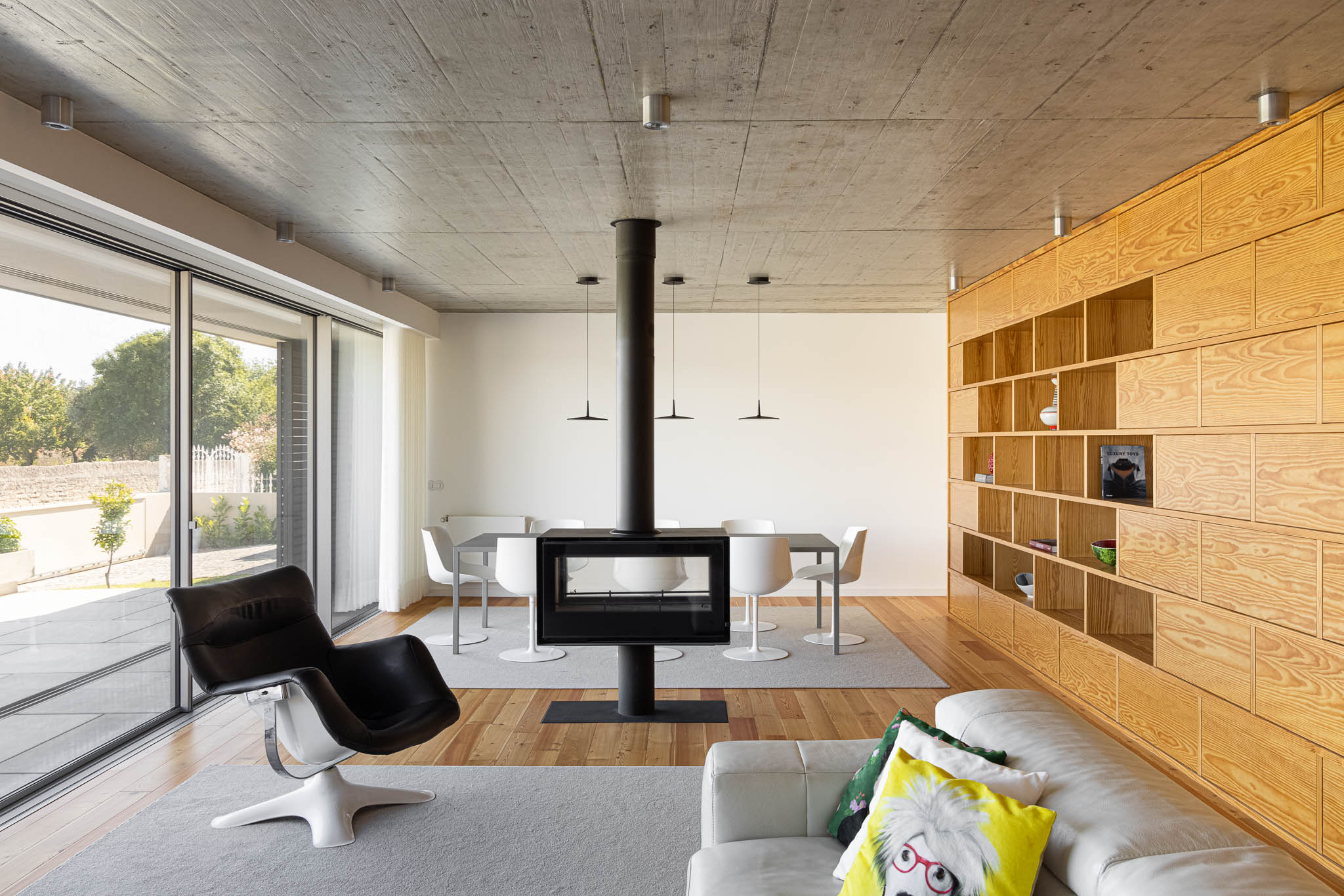 Sala de estar: Lareira central, estante em madeira, pavimento em madeira e alcatifa cinzenta. — Casa em Ílhavo arquitetura M2Senos Arquitectos em Ílhavo