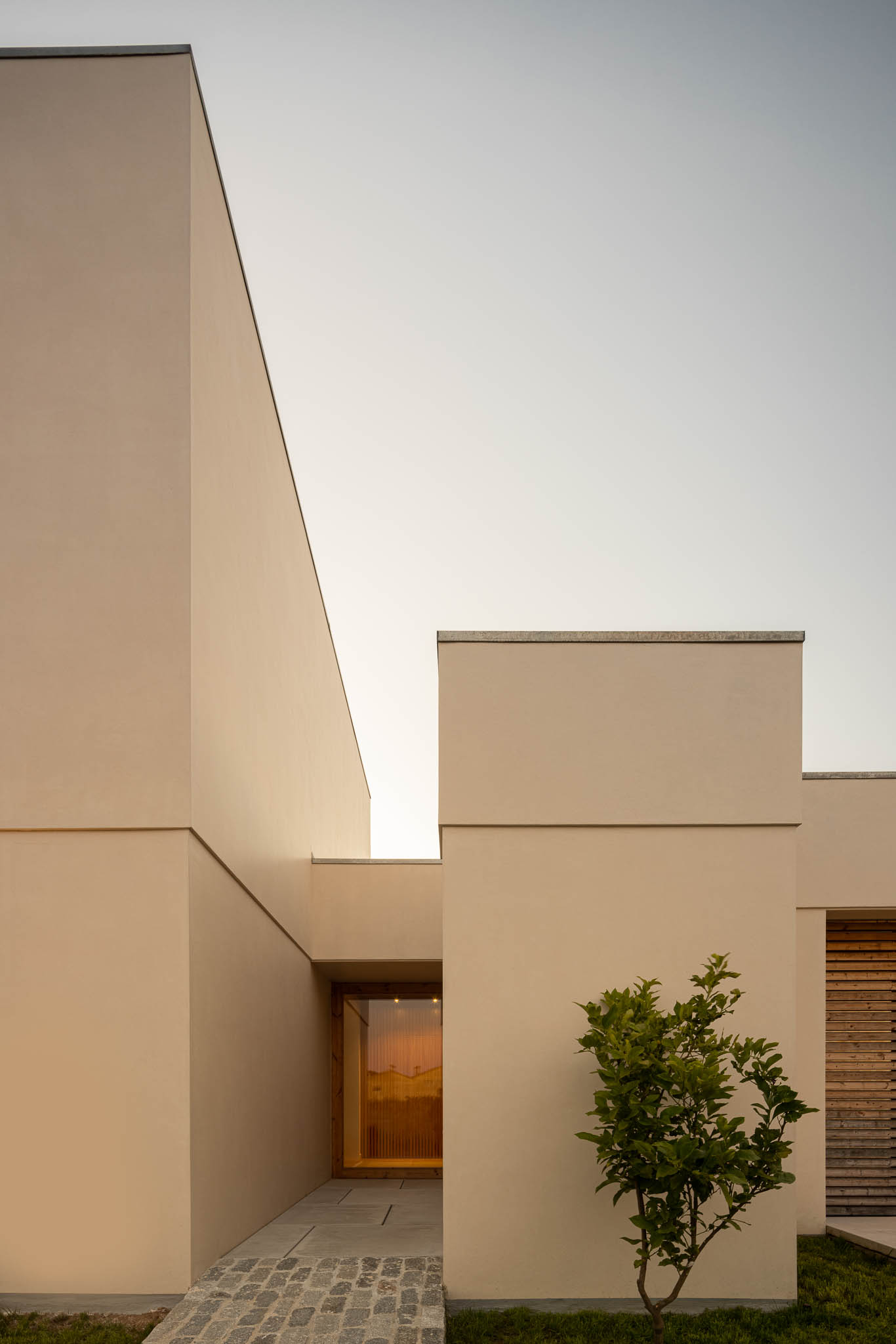 Fachada: Volume branco com entrada envidraçada e caminho em calçada portuguesa. — Casa em Ílhavo arquitetura M2Senos Arquitectos em Ílhavo