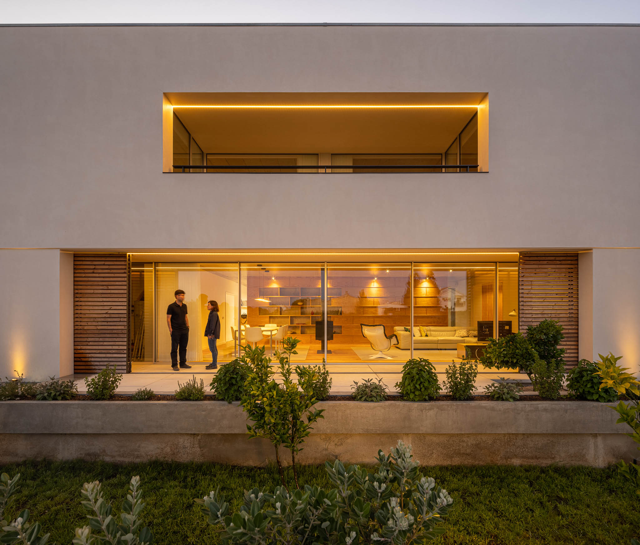 Fachada: Vista noturna da casa com iluminação linear e grandes janelas envidraçadas. — Casa em Ílhavo arquitetura M2Senos Arquitectos em Ílhavo