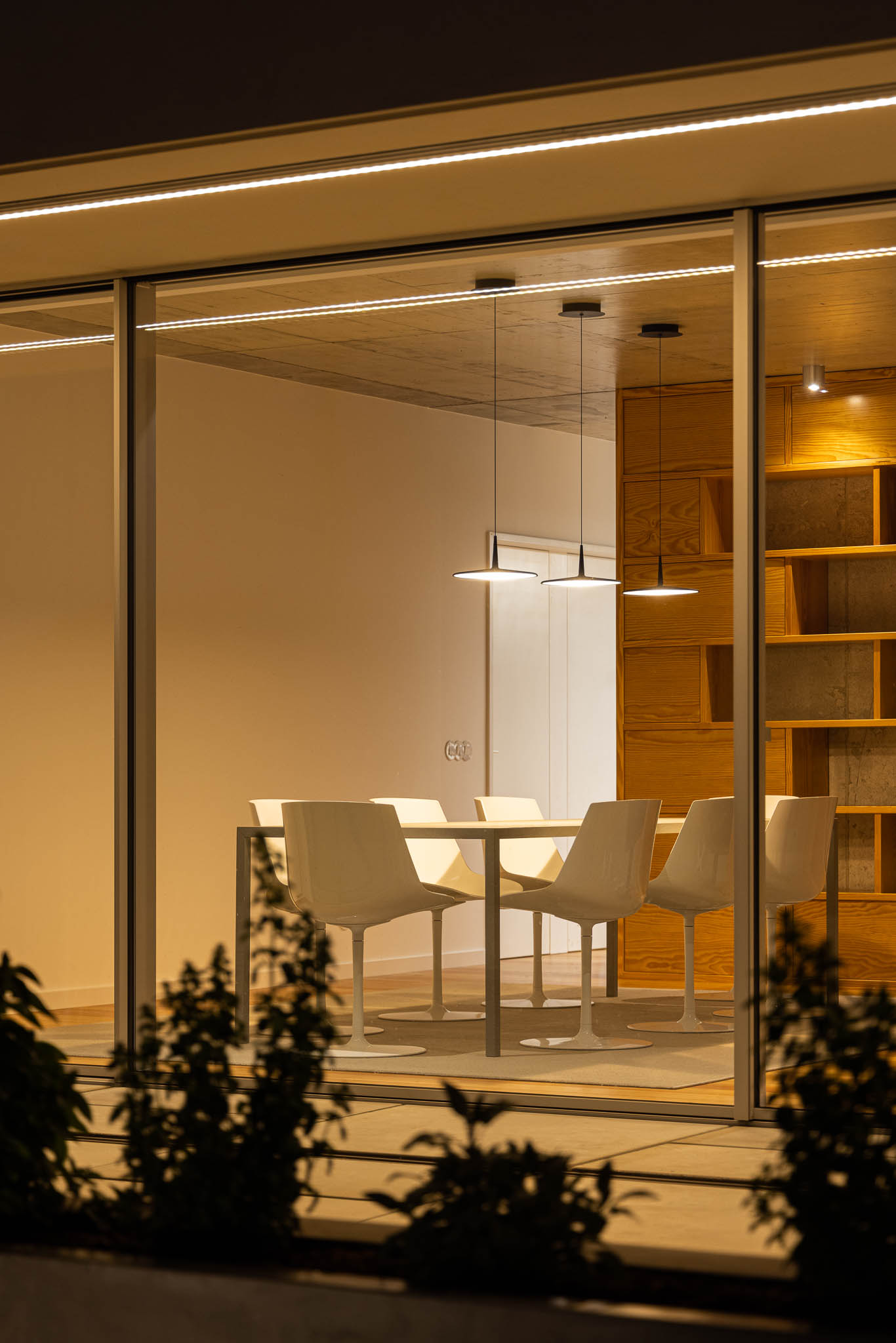 Sala de jantar: Mesa branca com cadeiras, estante em madeira e candeeiros suspensos. — Casa em Ílhavo arquitetura M2Senos Arquitectos em Ílhavo