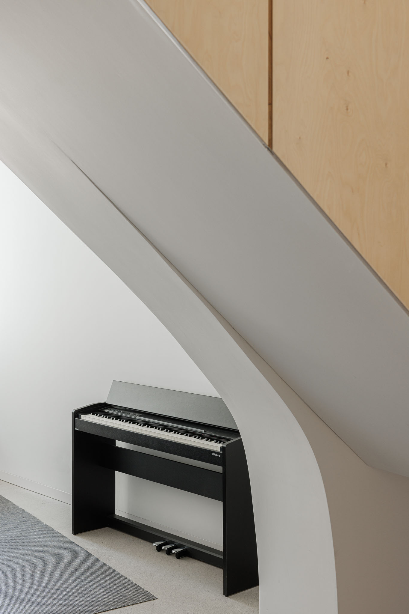 Escada: Piano preto sob a escada, pavimento em betão afagado e tapete cinzento. — Casa Vertical arquitetura Tsou Arquitectos em Porto