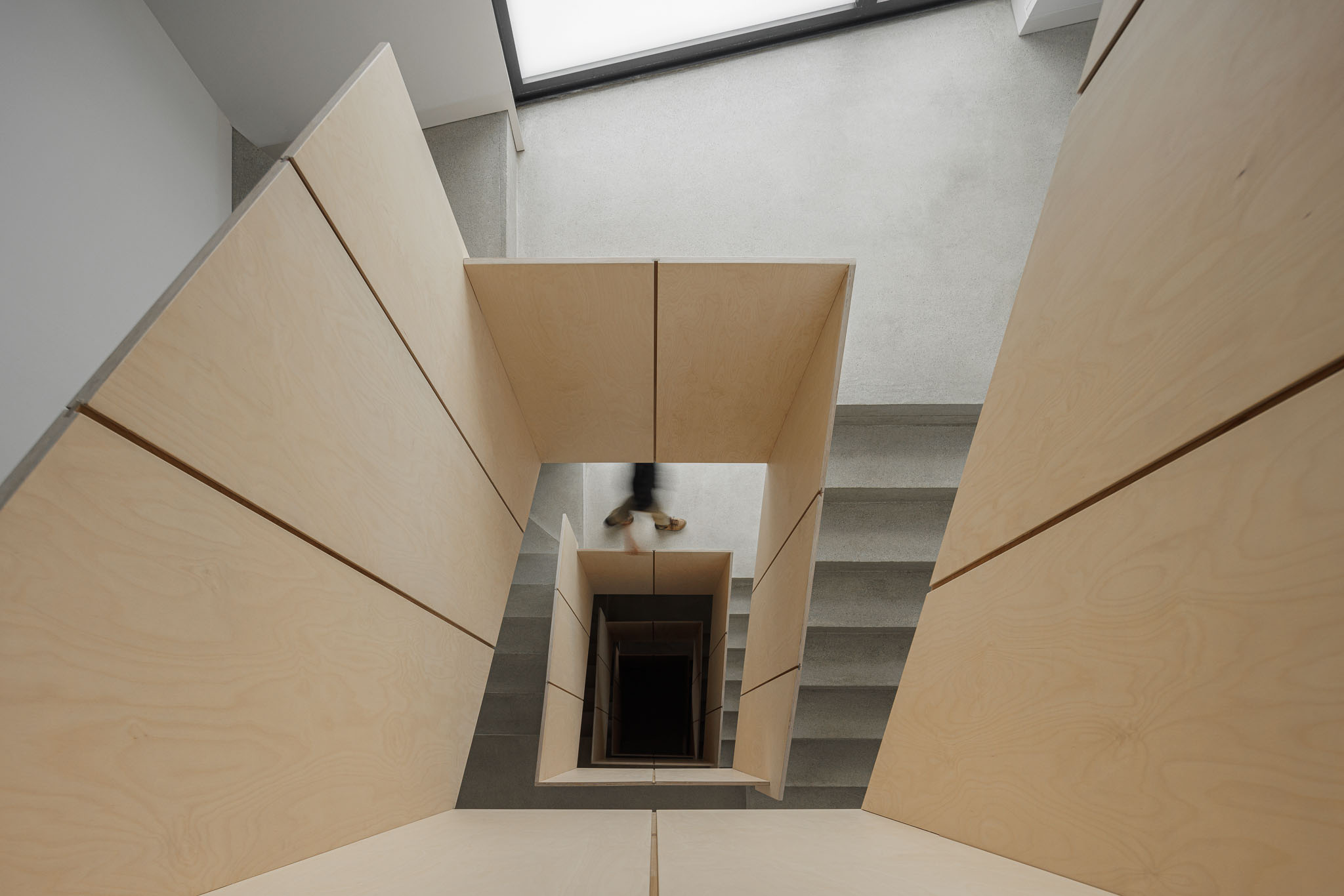 Escada: Vista vertical da escada em betão com corrimão em contraplacado claro. — Casa Vertical arquitetura Tsou Arquitectos em Porto